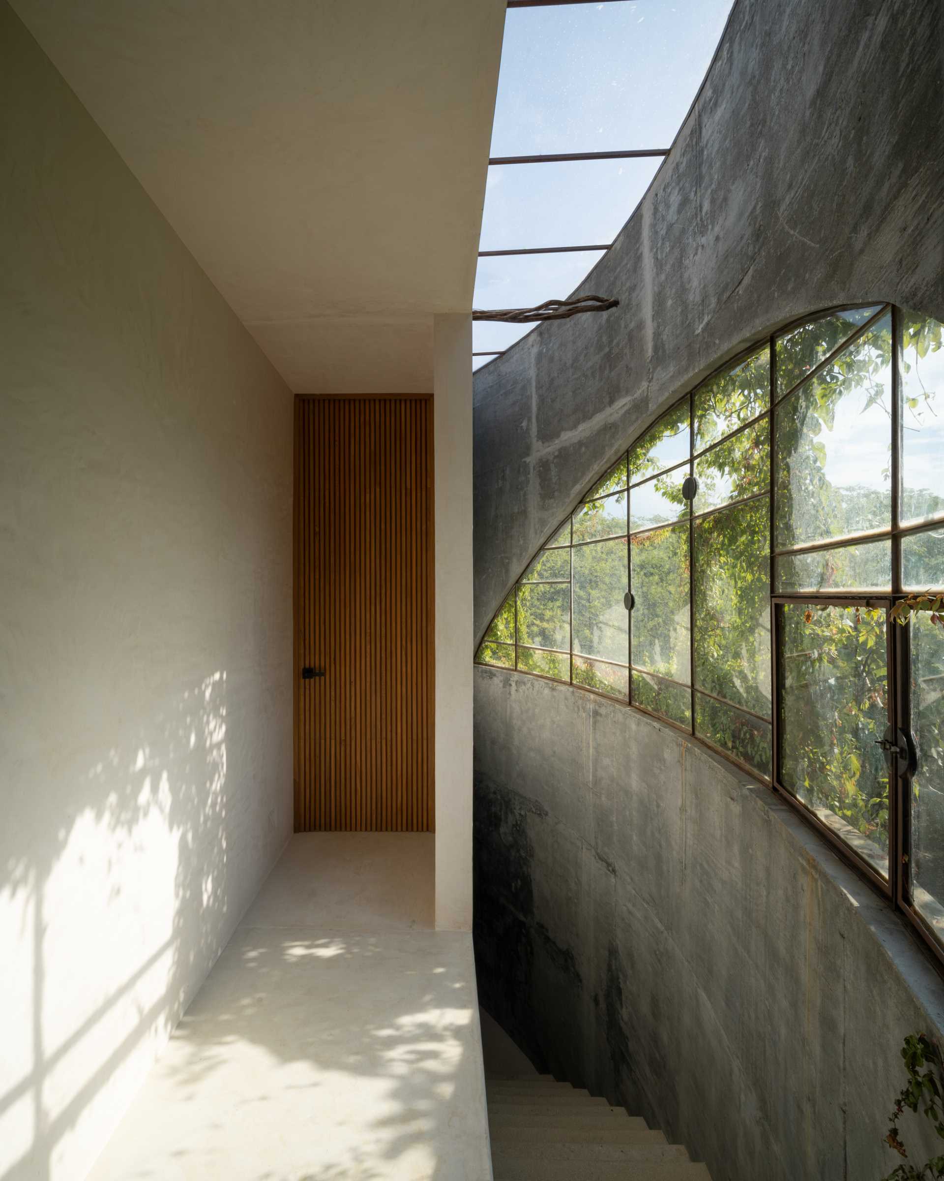 Stairs connect the main living floor with the primary bedroom upstairs and provide a close-up view of the curved concrete wall.