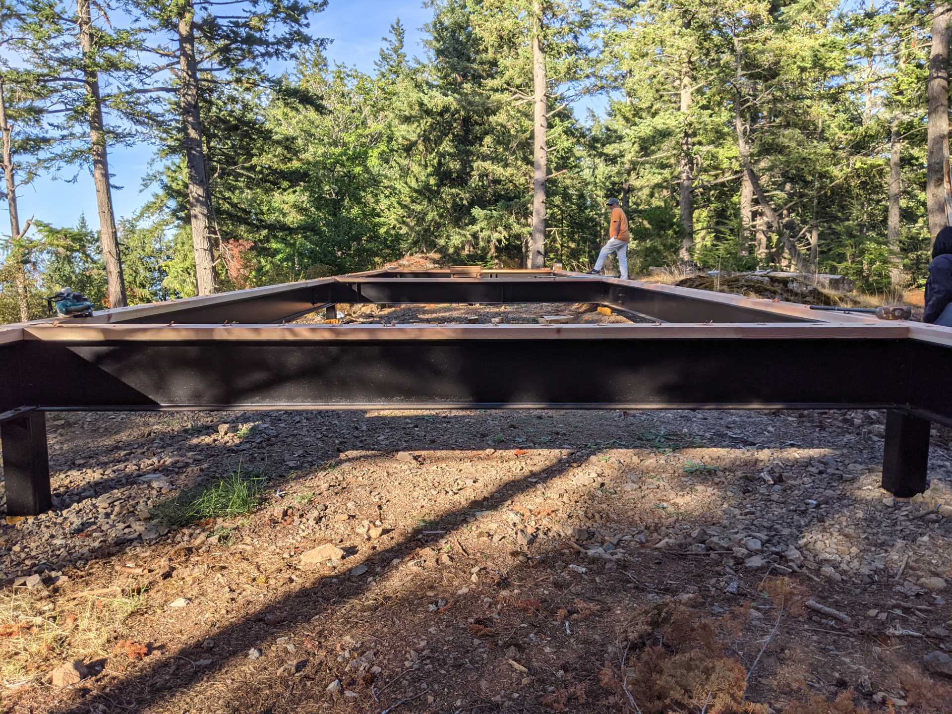 Construction photos of a modern island home with a cantilevered design, wood siding, and a standing seam metal roof.