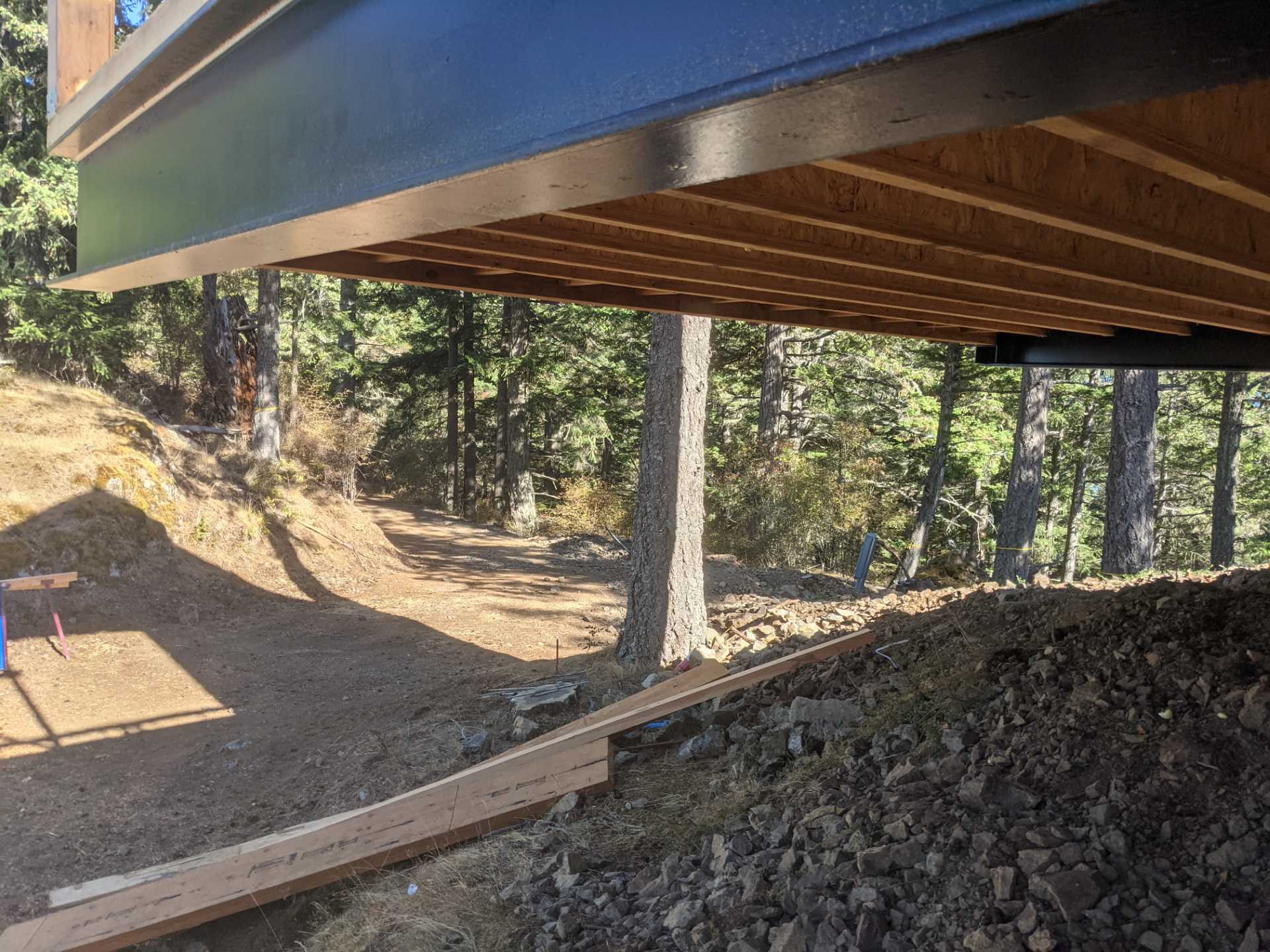 Construction photos of a modern island home with a cantilevered design, wood siding, and a standing seam metal roof.