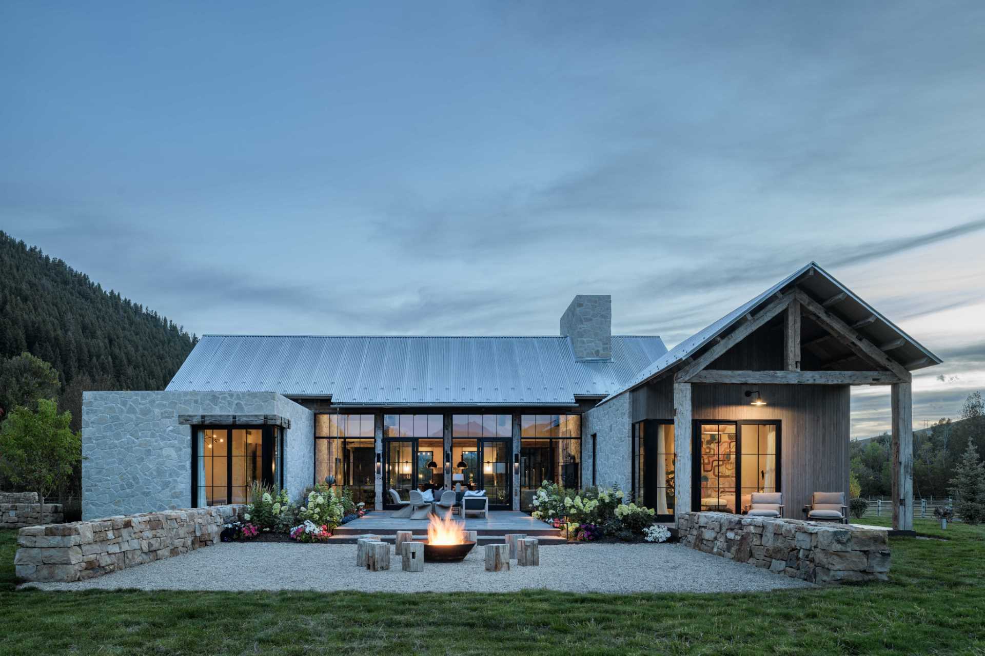 At the rear of this ranch home, the back courtyard features an outdoor fire pit, with floor-to-ceiling windows leading into the main living area.