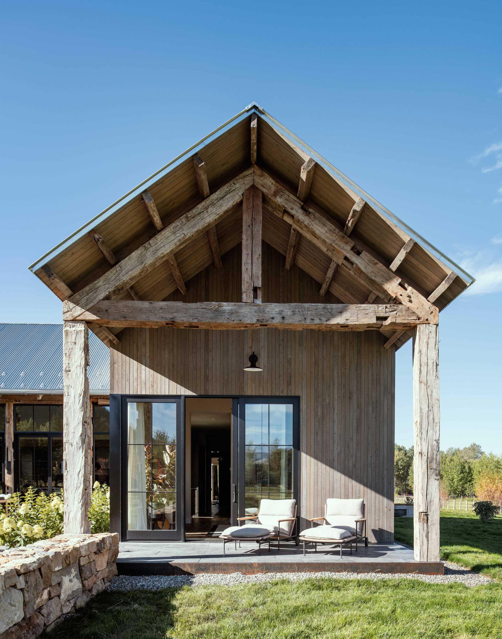 A contemporary ranch home has rustic hand-hewn timbers that add character and charm to an outdoor patio.