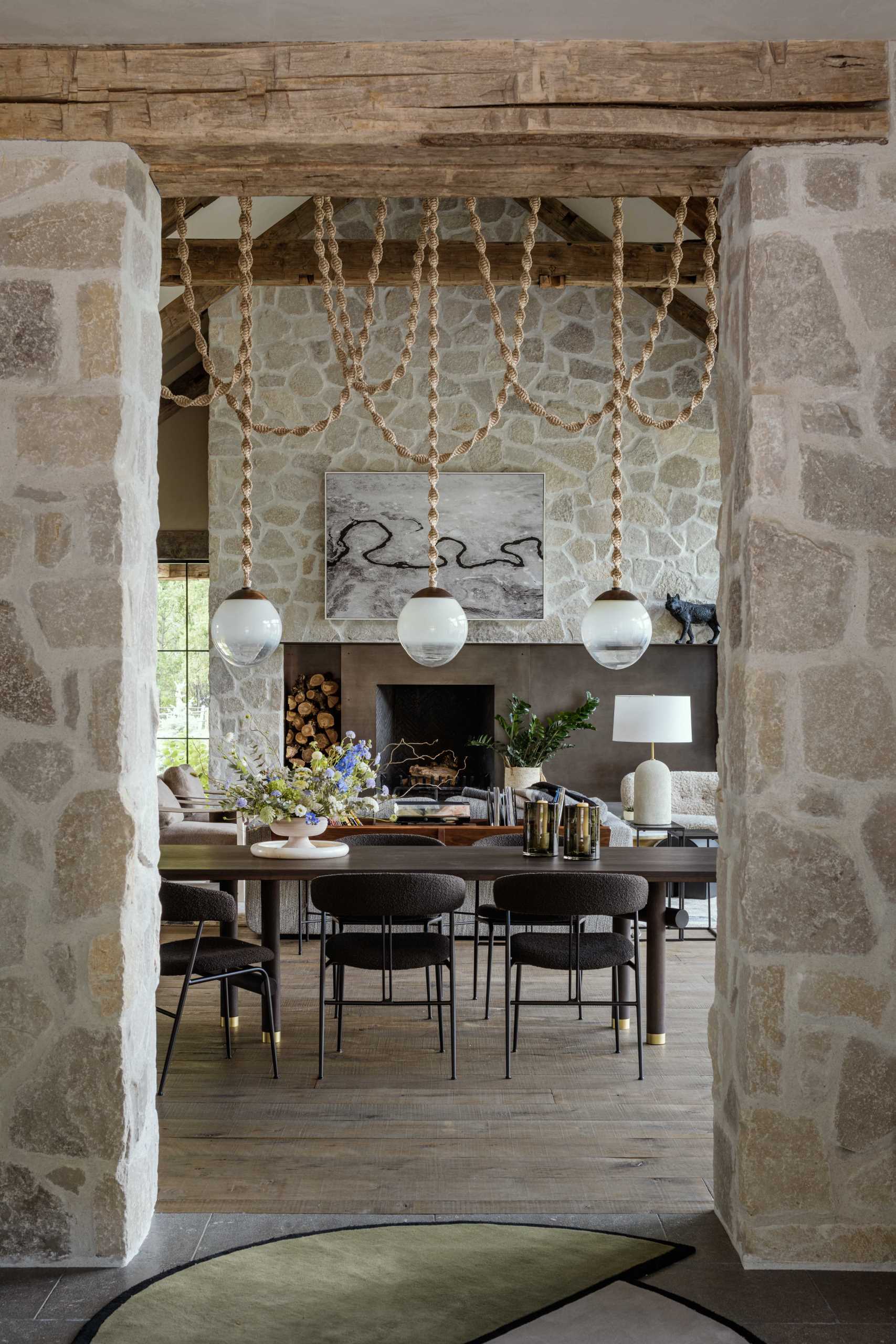 An opening between the living and kitchen area in a contemporary ranch home is framed by stone and custom light fixtures.