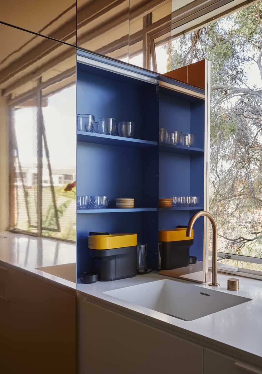 In the kitchen of this micro apartment, the brass pod opens to reveal blue kitchen shelves, adding a hidden pop of color to the interior.