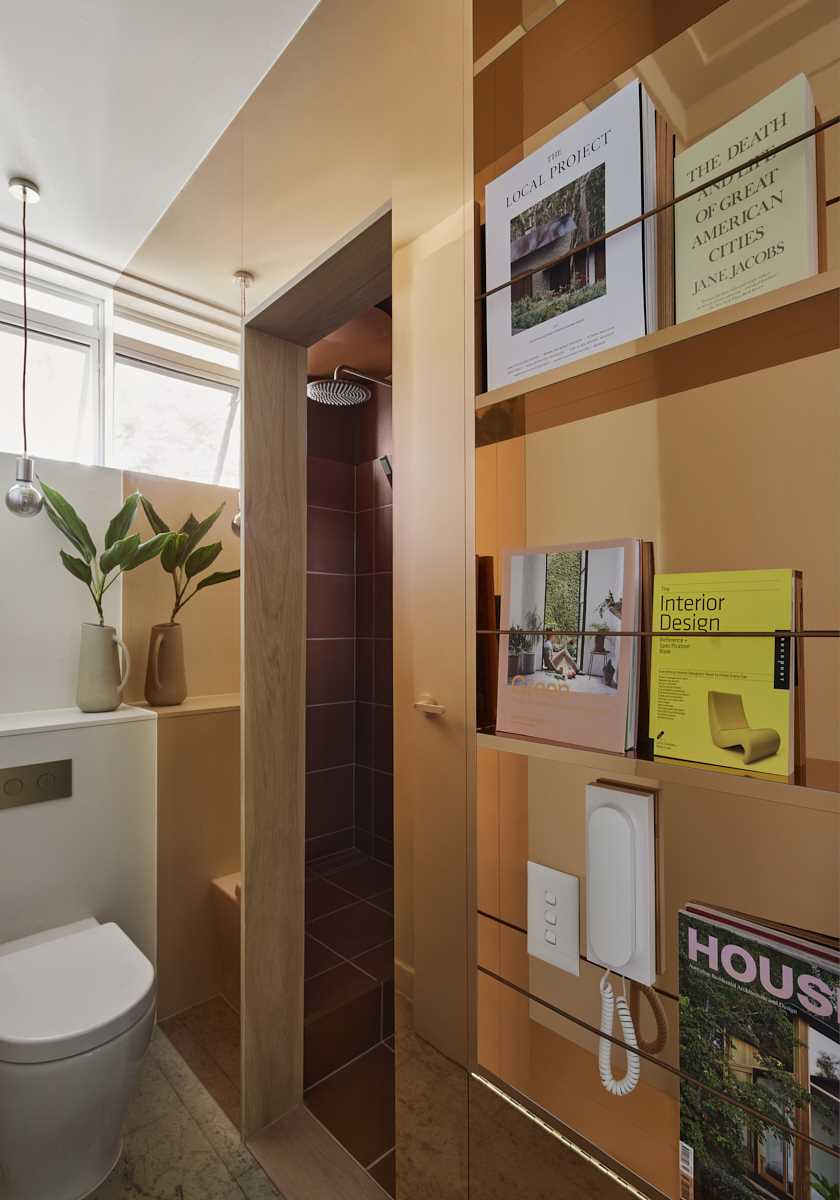 A modern bathroom within a brass clad pod afeatures a warm terracotta color scheme.