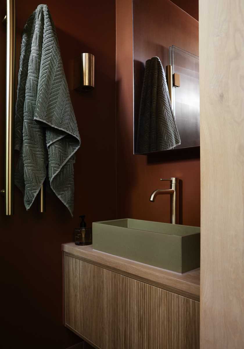 A modern bathroom vanity features a warm terracotta color scheme.