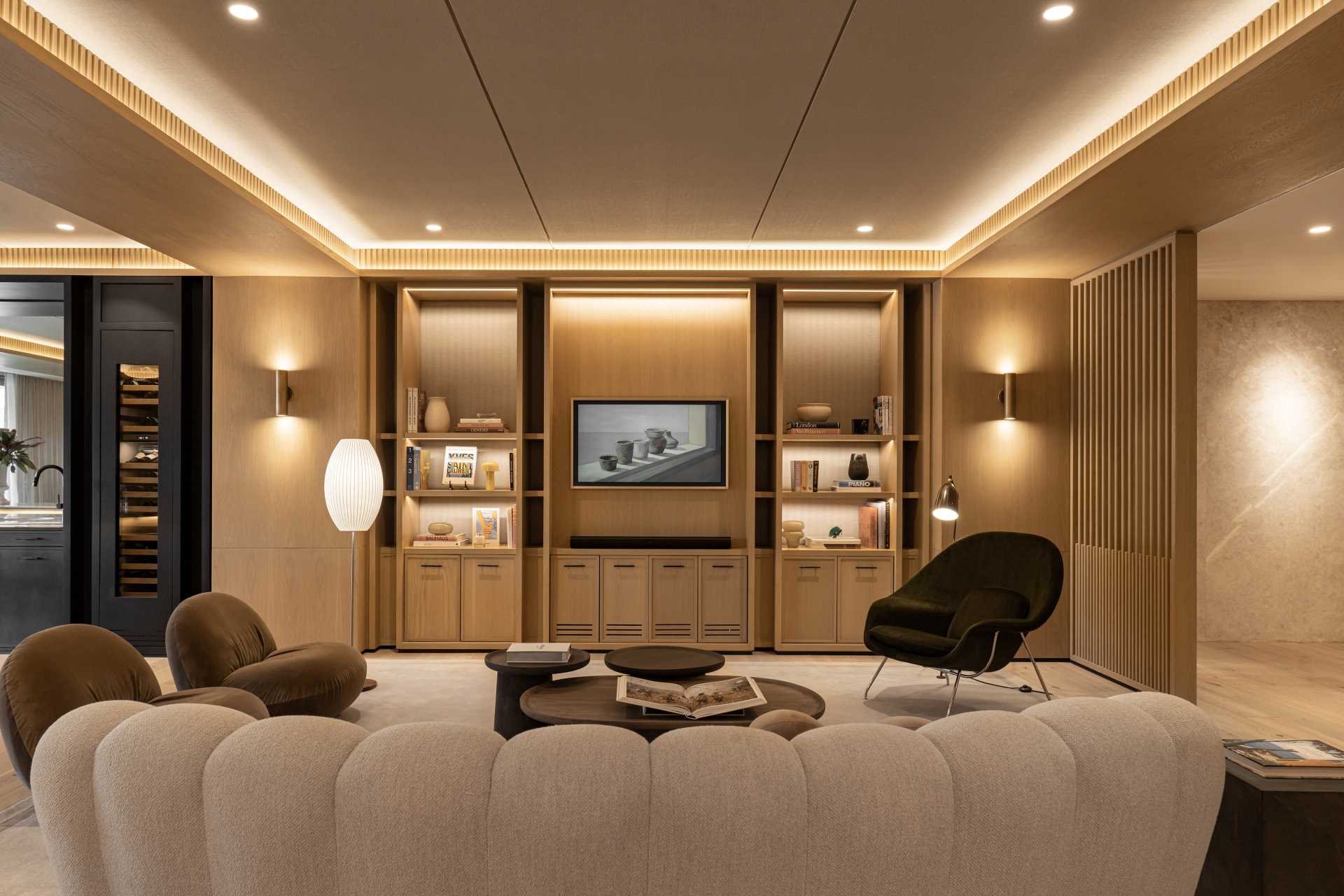 A modern living room with bespoke cabinetry and hidden lighting.
