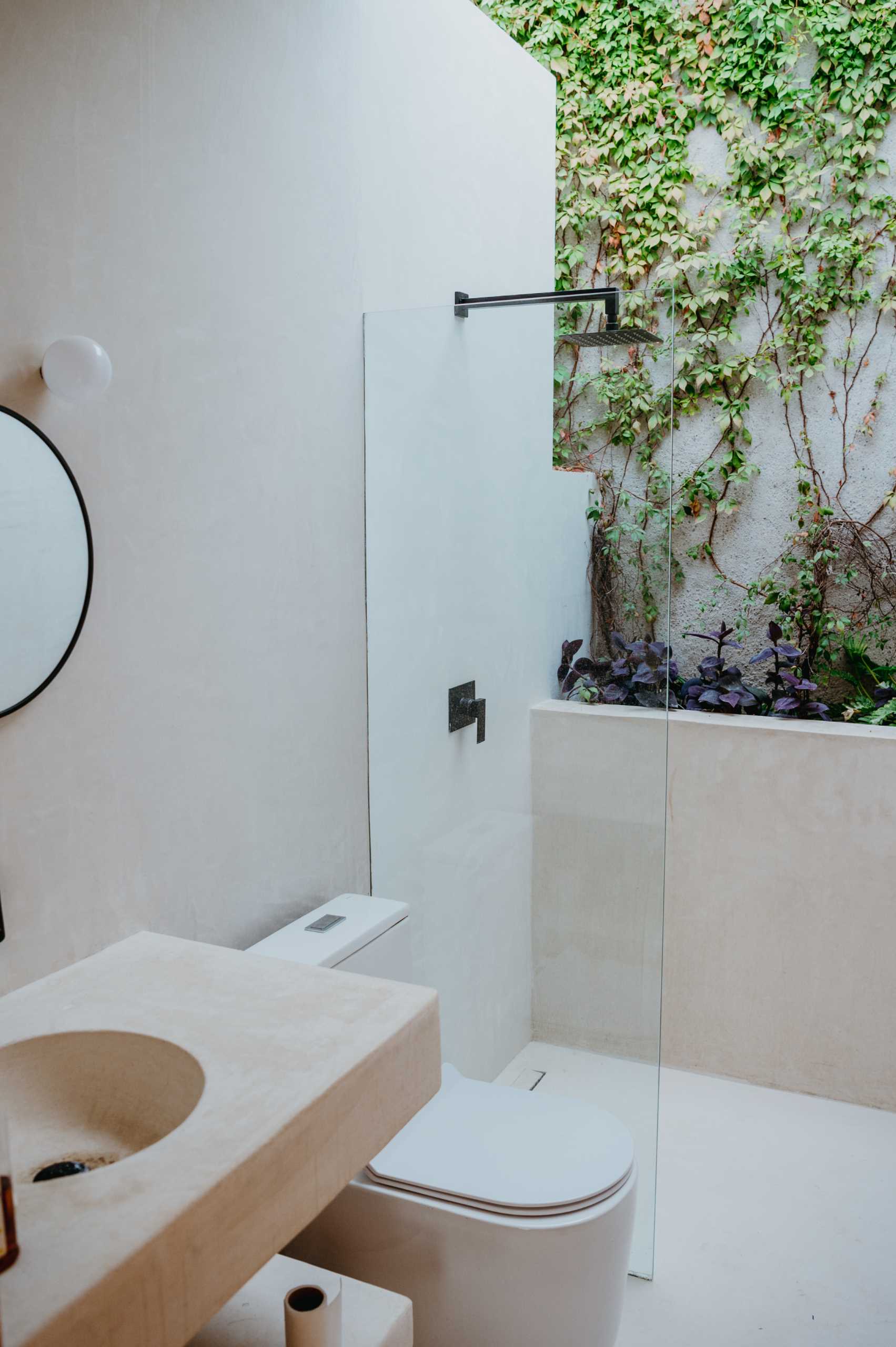 A modern bathroom includes a wall with ivy, creating a feeling of being outdoors.