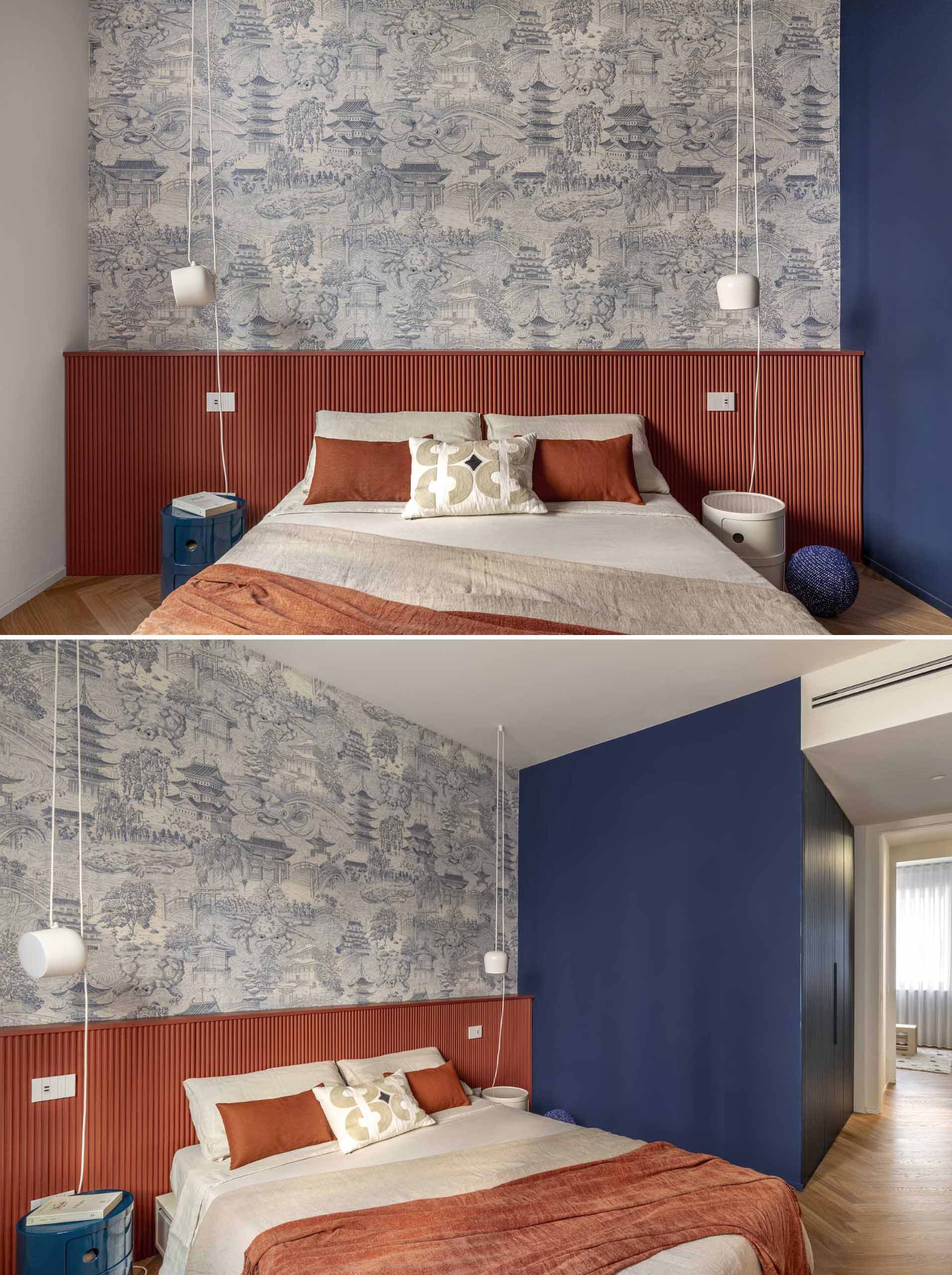 In this primary bedroom, color has been used to define the areas, with a deep terracotta used as a headboard that spans the width of the wall, while deep blue cabinetry is home to the closet. An Asian-inspired wallpaper complements the blue accents in the room.