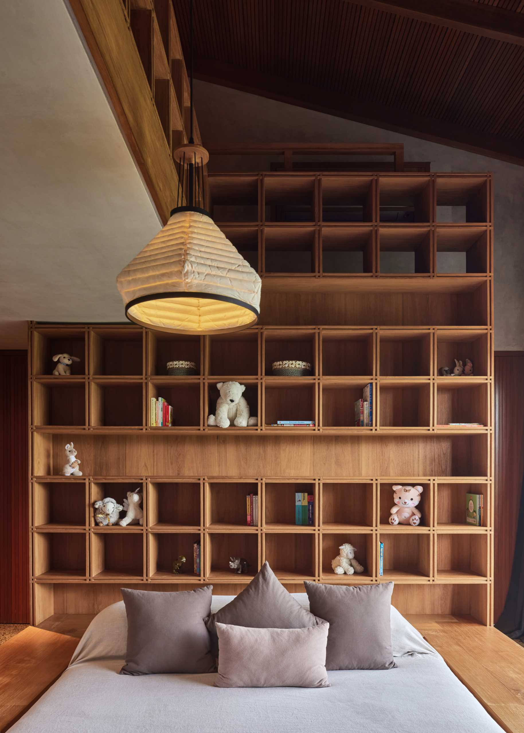 In this bedroom, a wood frame surrounds the bed, while a custom shelving unit lines the wall.