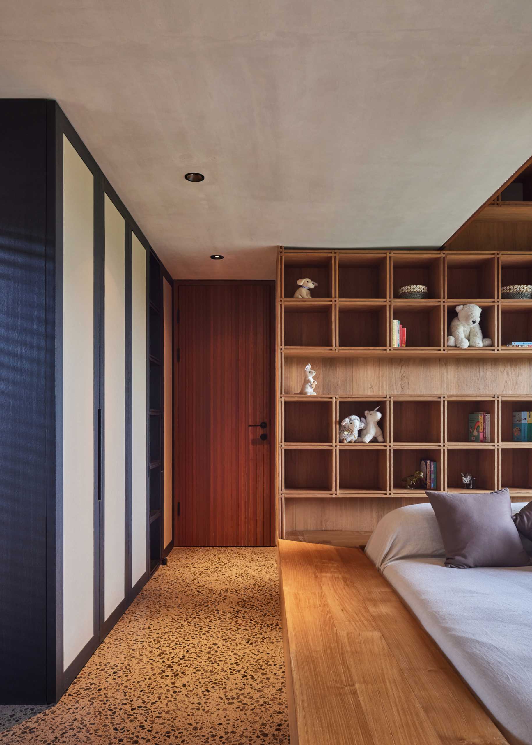 In this bedroom, a wood frame surrounds the bed, while a custom shelving unit lines the wall.