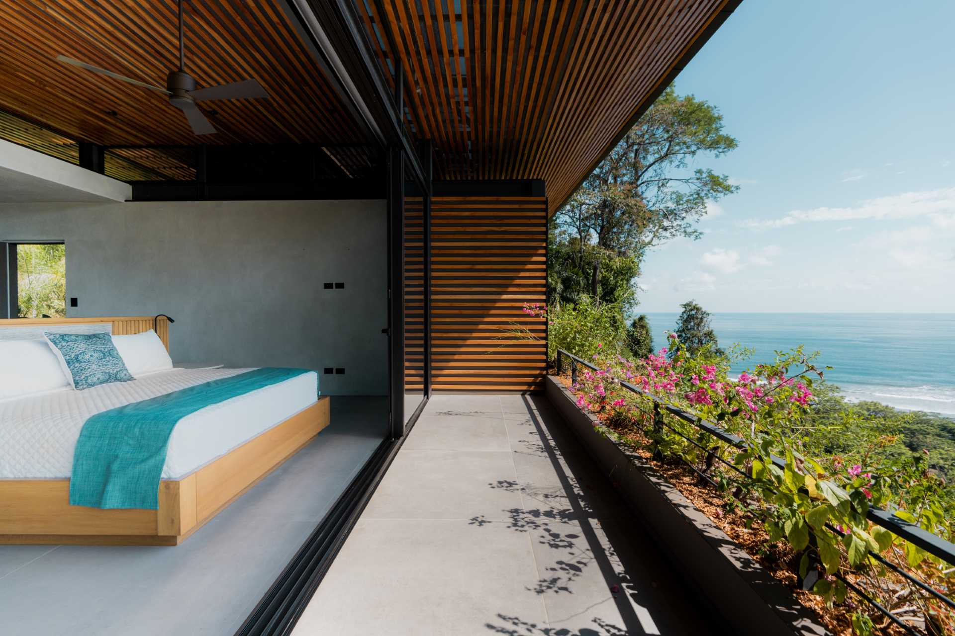 A modern bedroom that opens to a balcony with water views.