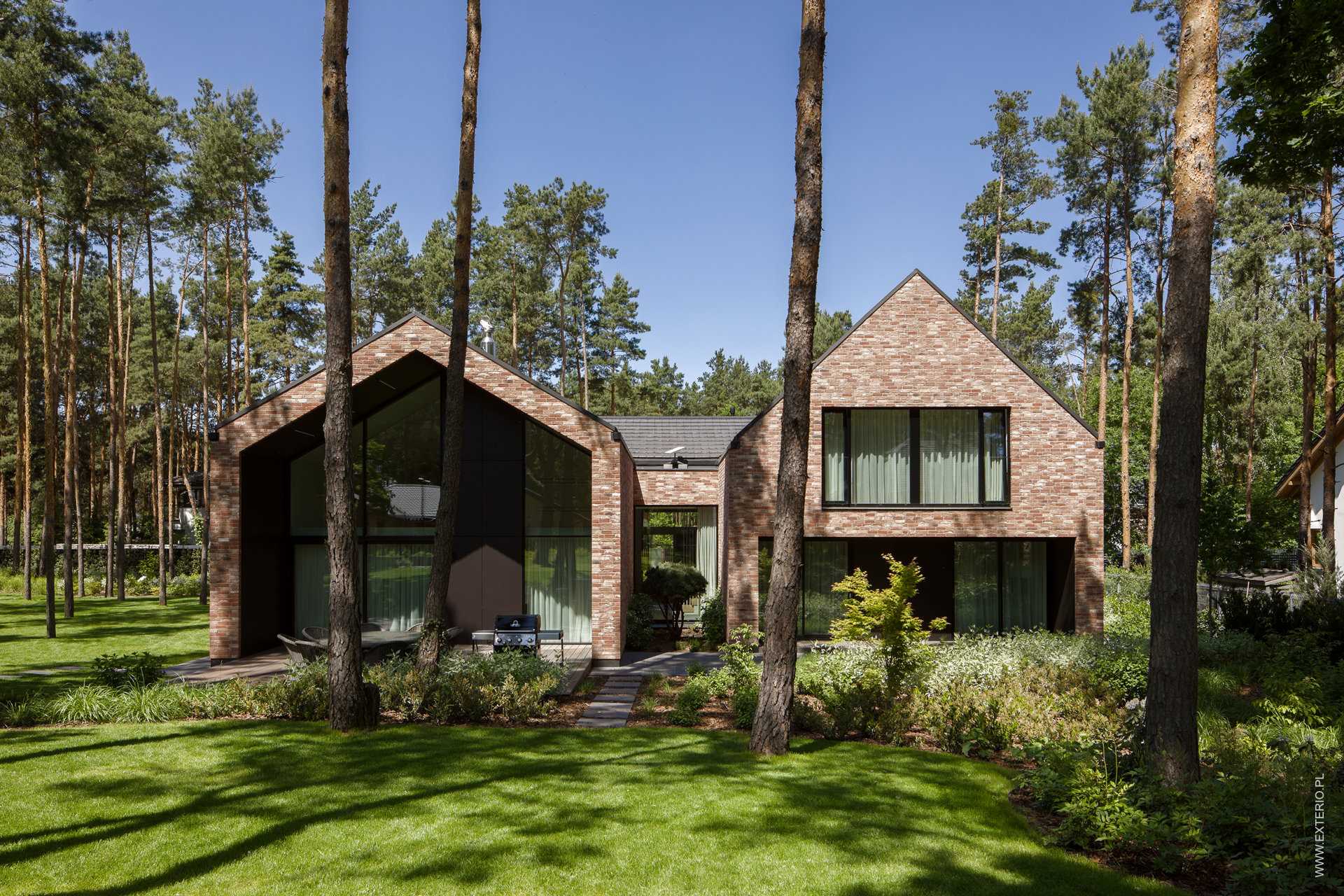 A modern home with a handmade rustic brick exterior, and dark ceramic roof tiles.