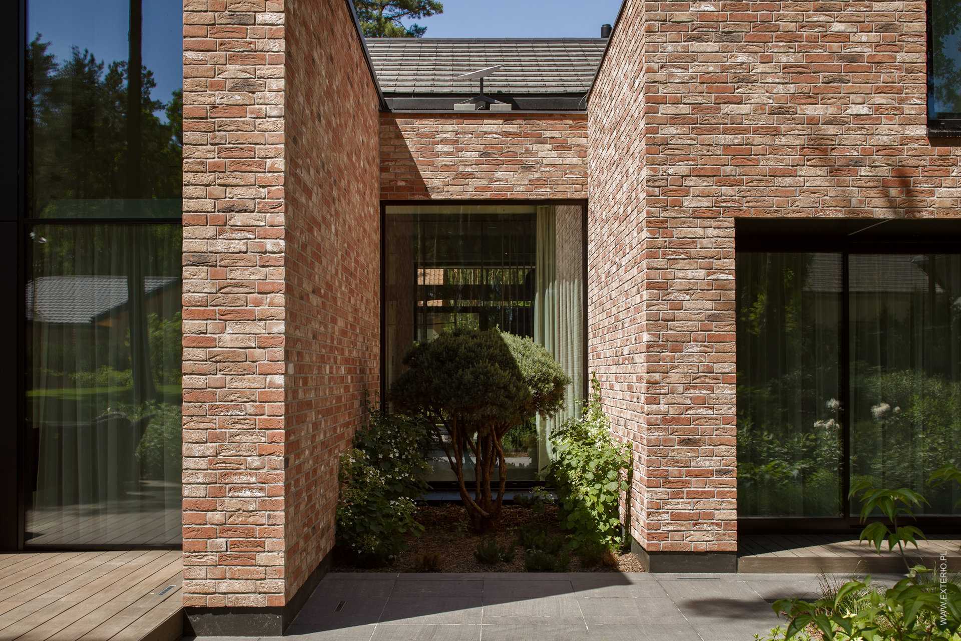 A modern home with a handmade rustic brick exterior, and dark ceramic roof tiles.