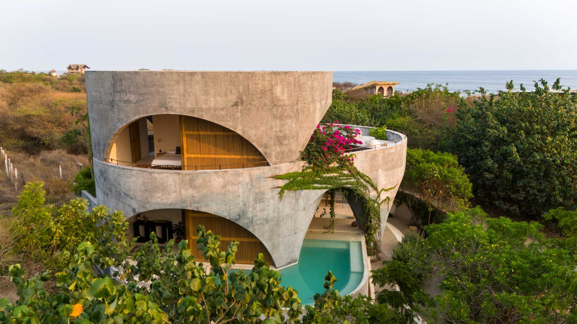 A modern concrete home with a round design and open arches.