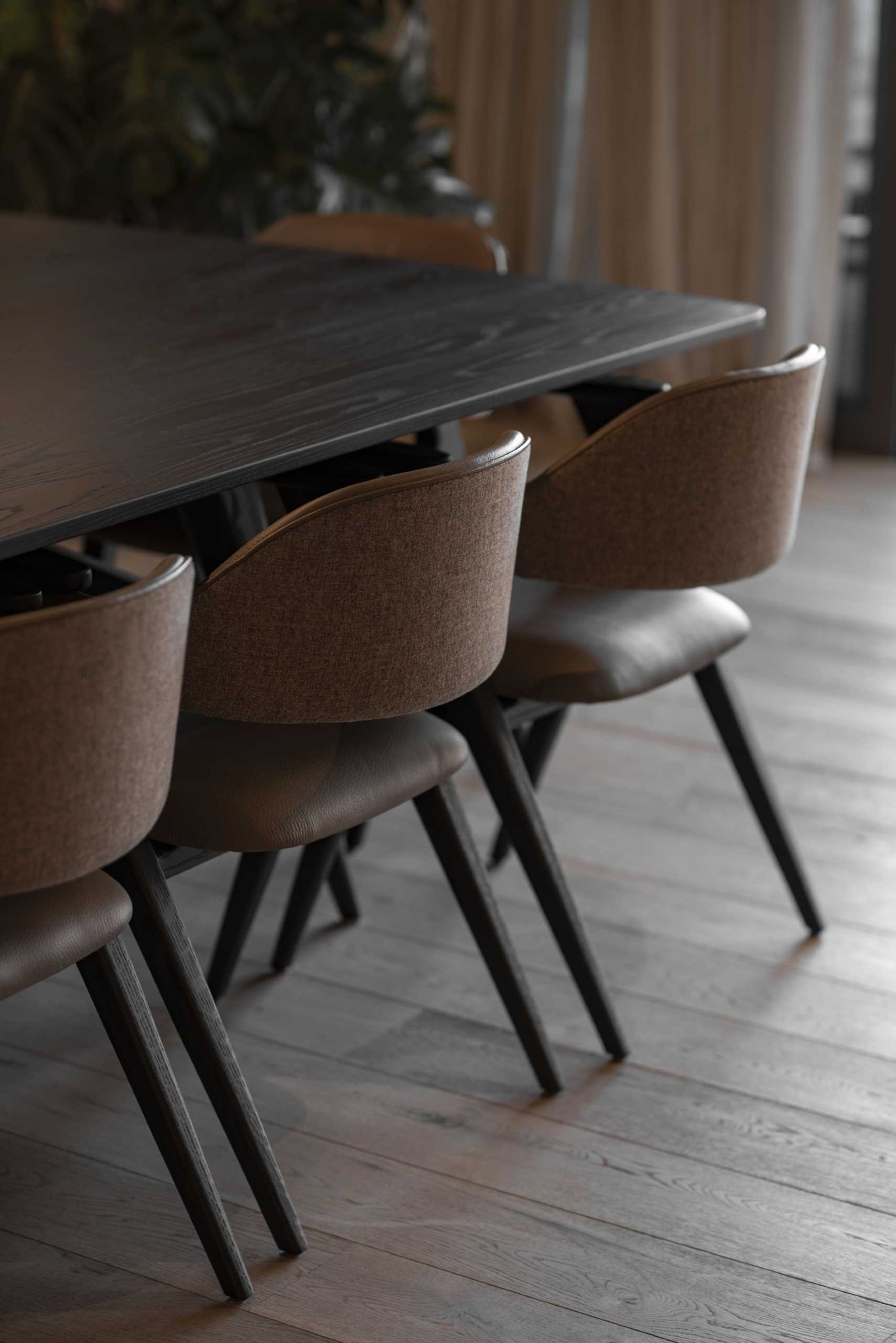 This open-plan dining room has a mirrored wall and features the Luana chair from Piztola, with its dark wood and leather tones, adding a touch of sophistication.