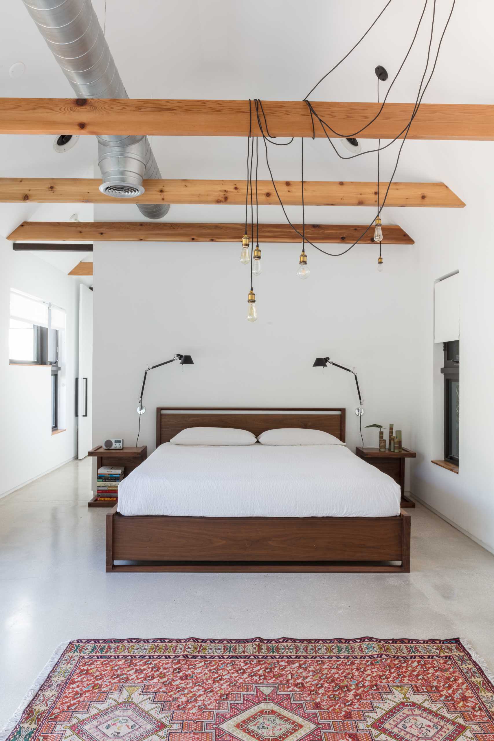 A primary bedroom with wood furniture, concrete floors, and exposed wood beams.