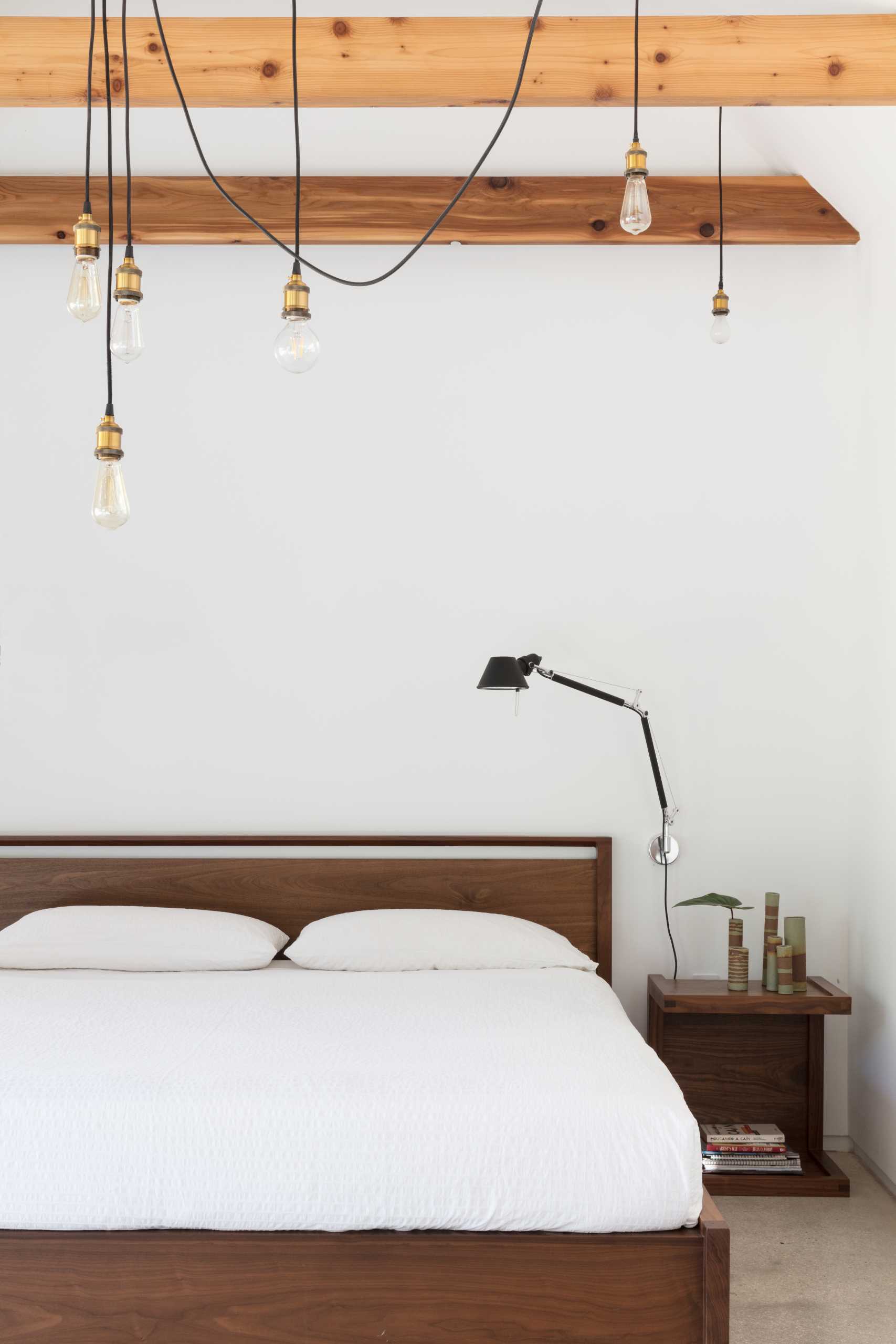 A primary bedroom with wood furniture, concrete floors, and exposed wood beams.