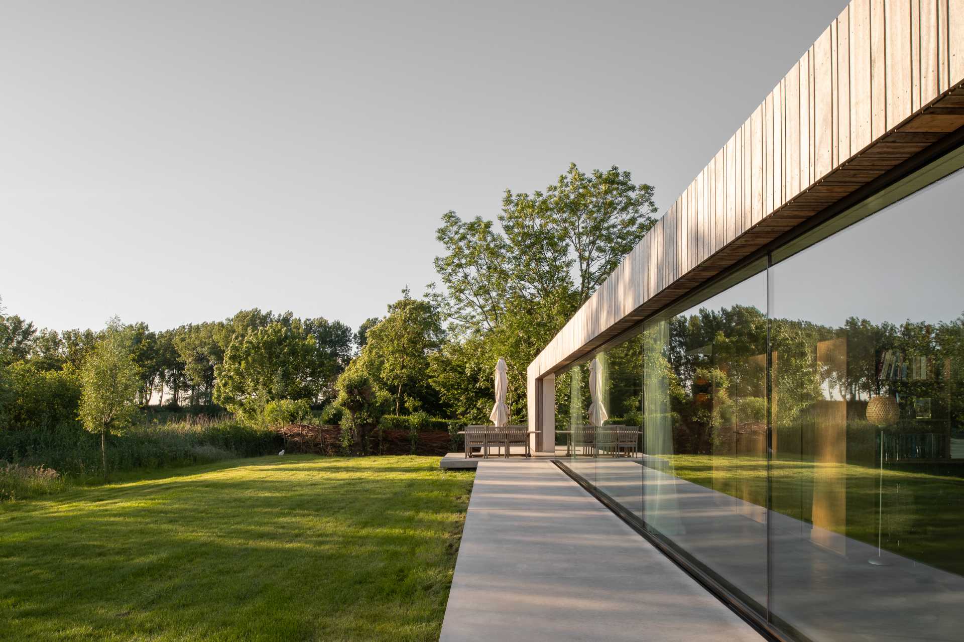 The roof material of this modern home extends down the facade, while glass walls flood the interior with natural light.