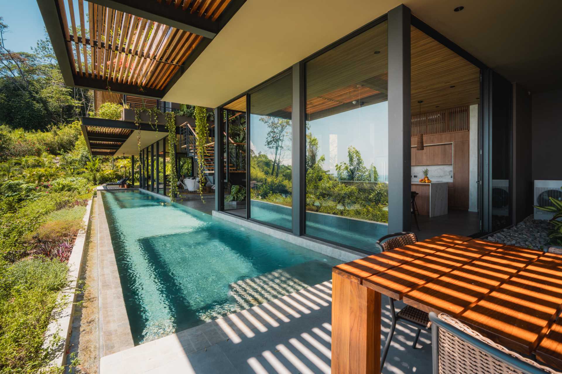 A modern tropical home has a 24-meter infinity lap pool balanced over a steep incline.