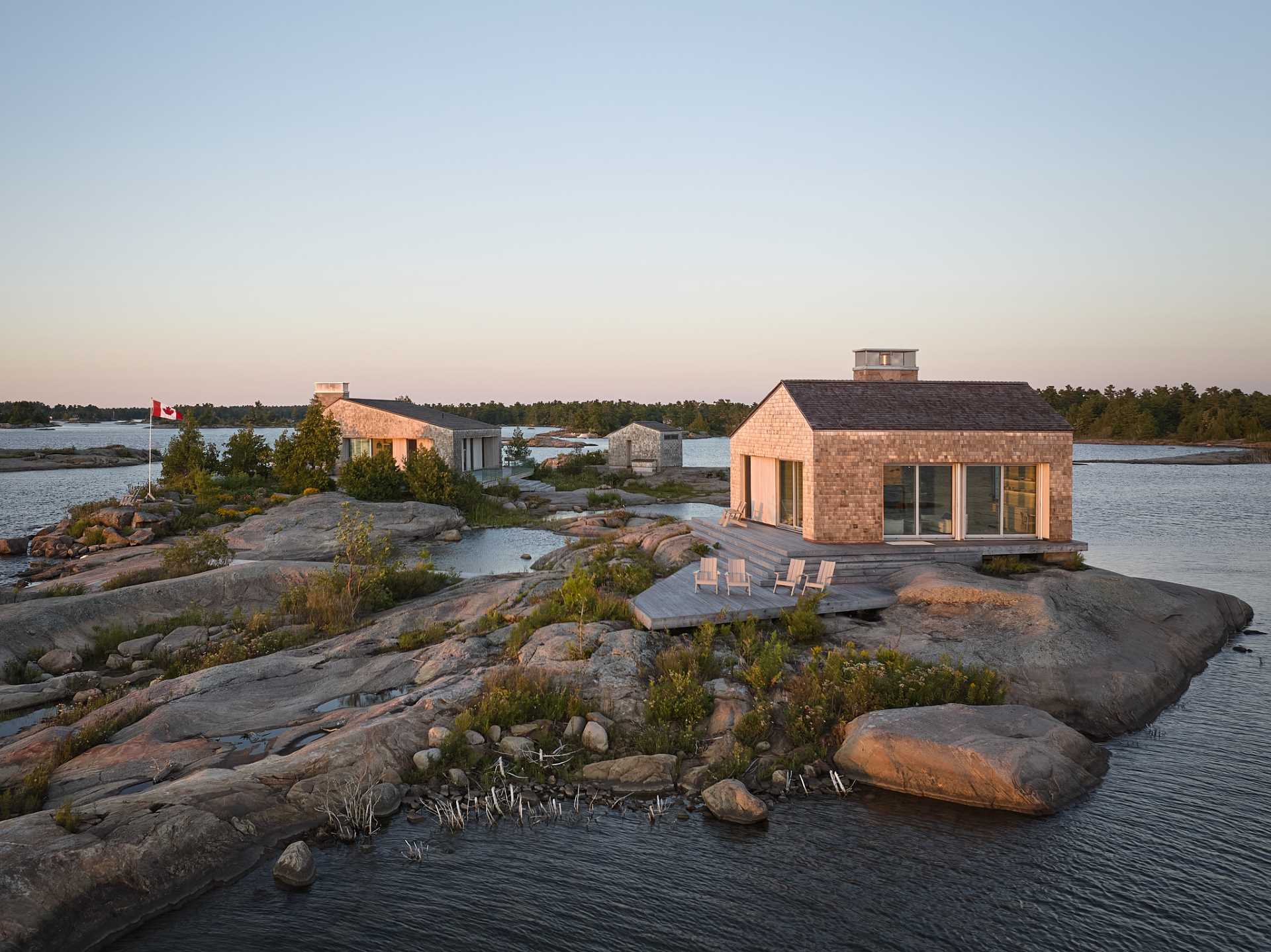 A contemporary cottage that comprises a cluster of buildings, each clad in shingles.