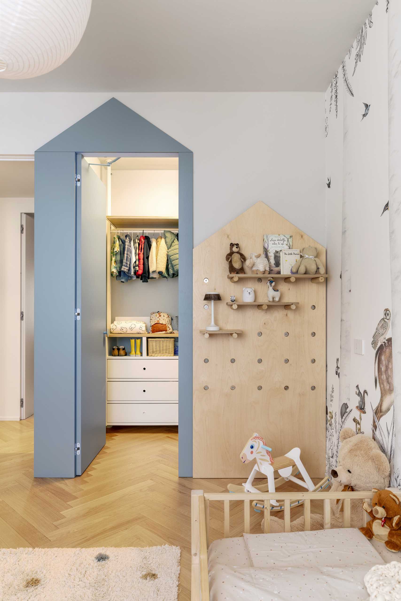 In a child's bedroom, a soft dusty blue has been used to create a contemporary and fun look that also includes a walk-in closet, a pegboard wall with shelves, and a woodland mural.