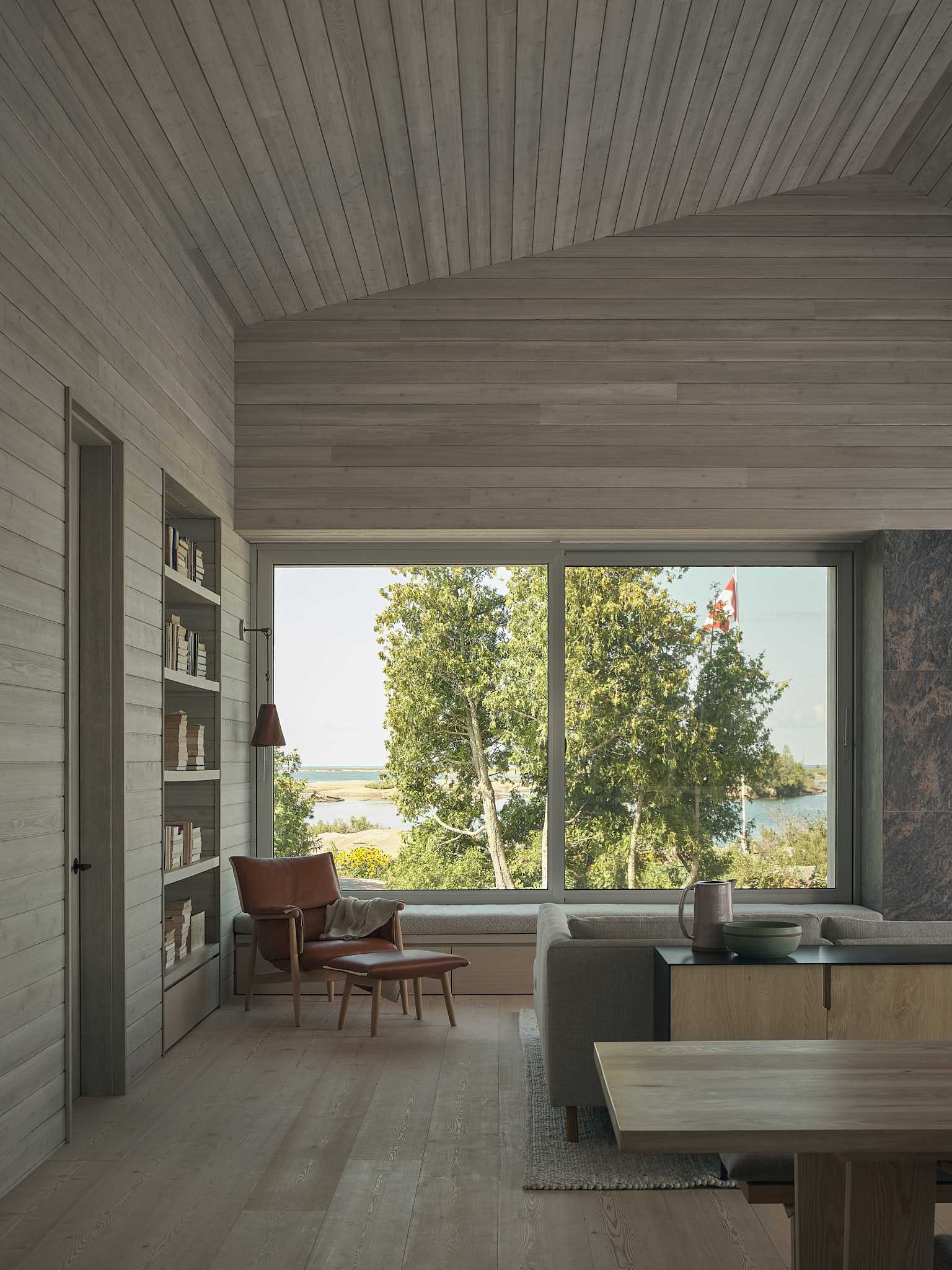 A modern cottage has a living room with a fireplace, a window seat, and a built-in bookshelf.