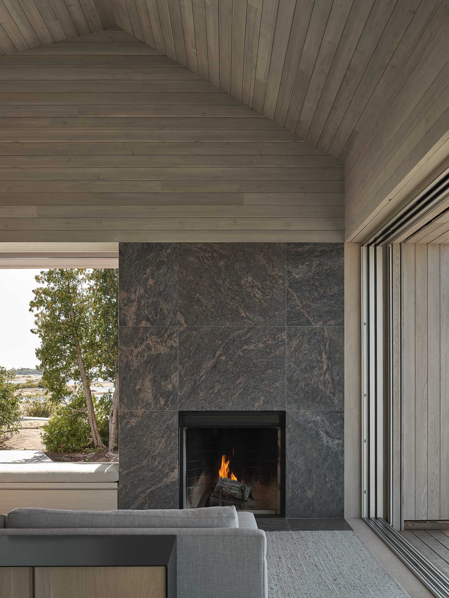 In this living room, matching wood planks line the cathedral ceiling, providing a contemporary interpretation of a gabled wood form found in traditional cottages.