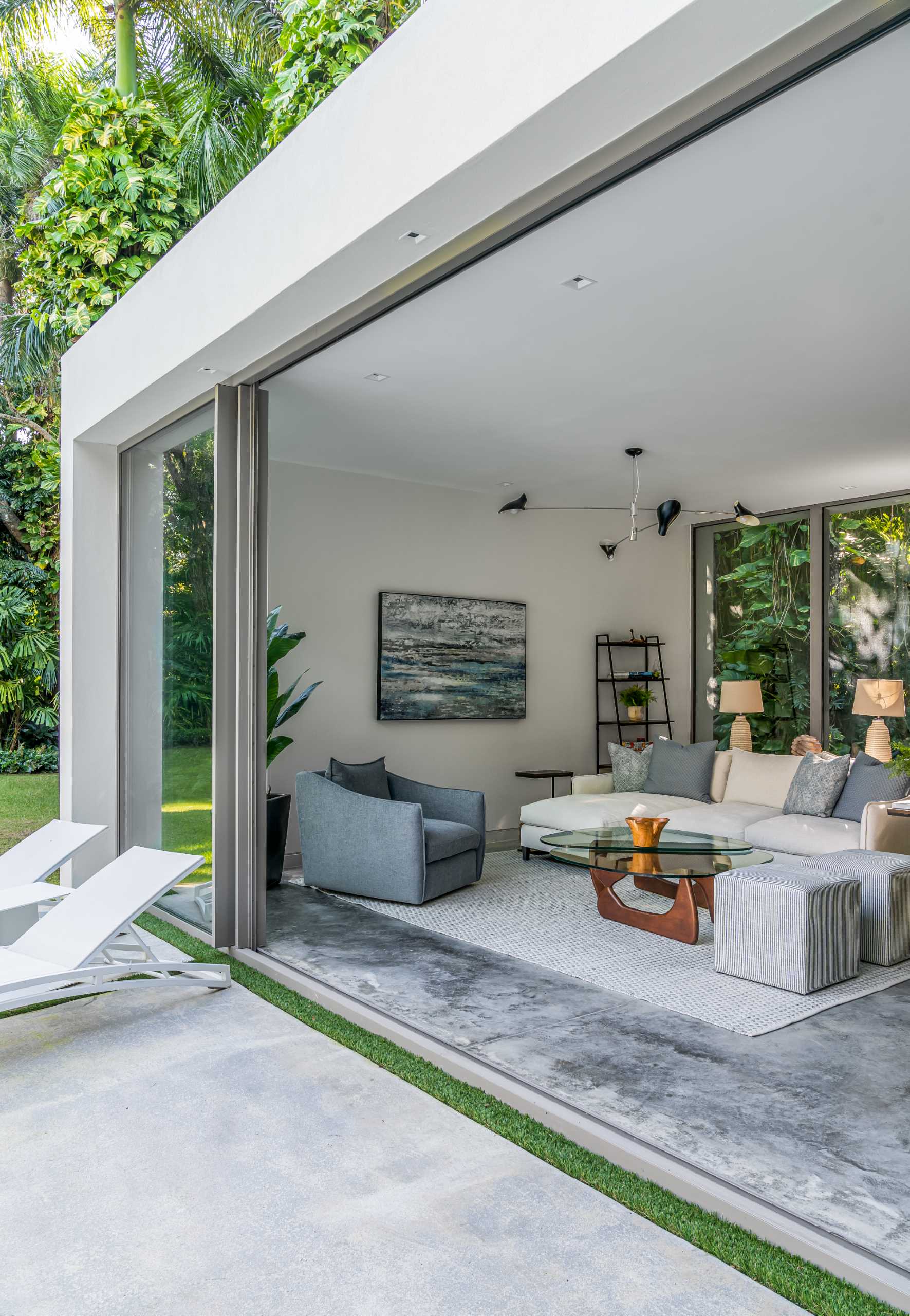 A modern backyard pavilion includes a sitting area that looks out onto the pool and towards the primary home.