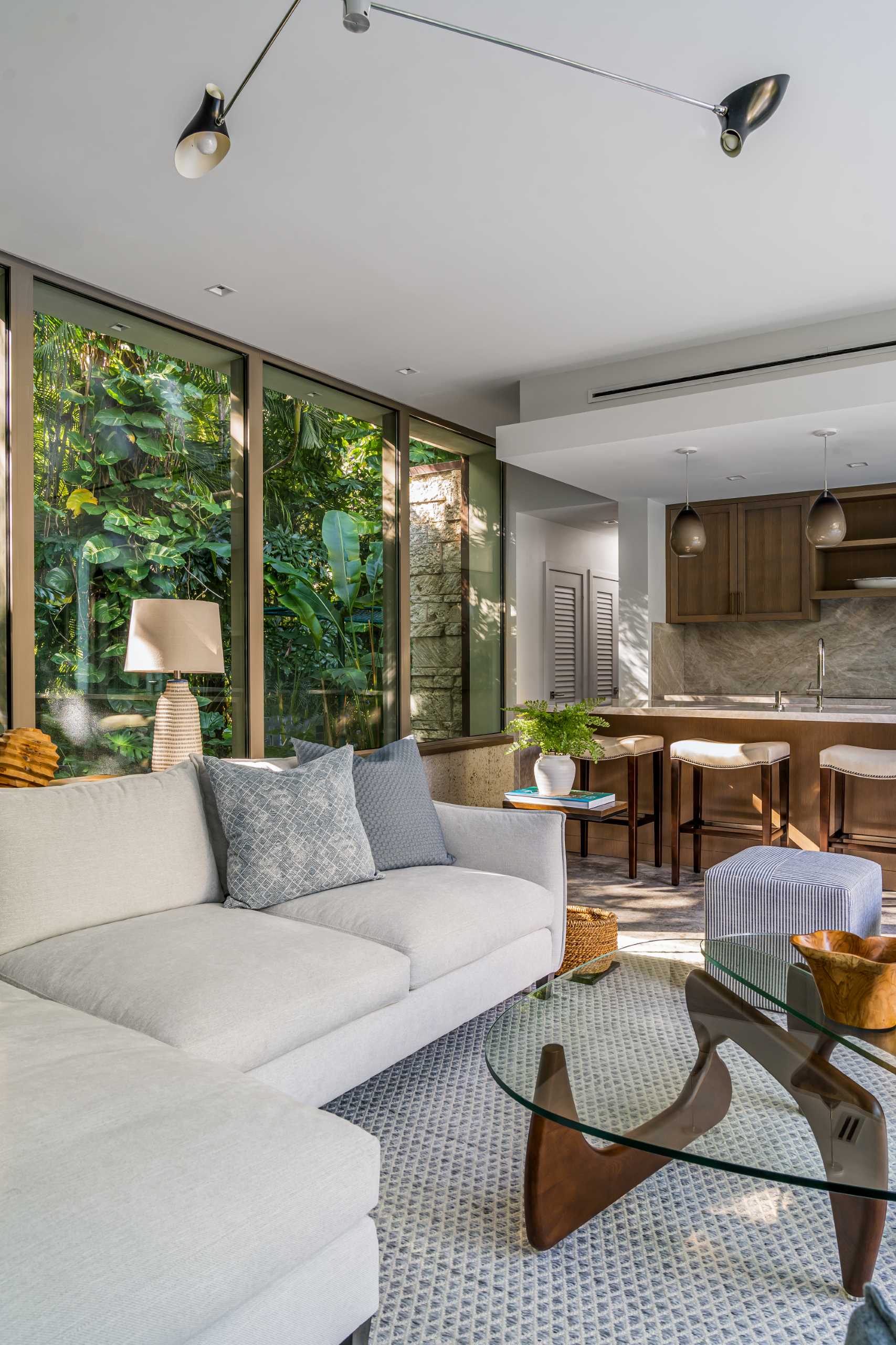 A modern backyard pavilion includes a sitting area that looks out onto the pool and towards the primary home.