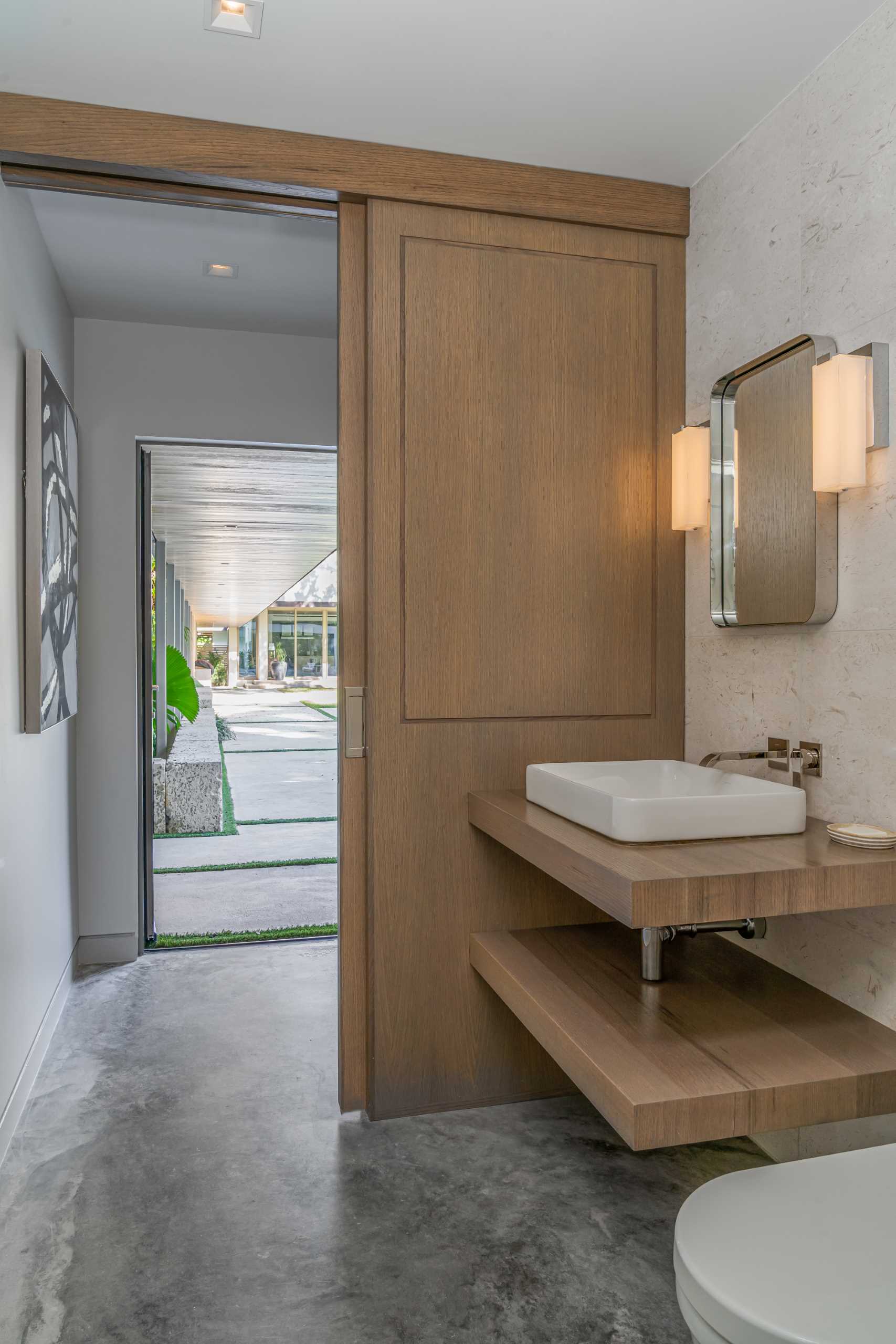 A bathroom is hidden behind a wood sliding door that complements the vanity.