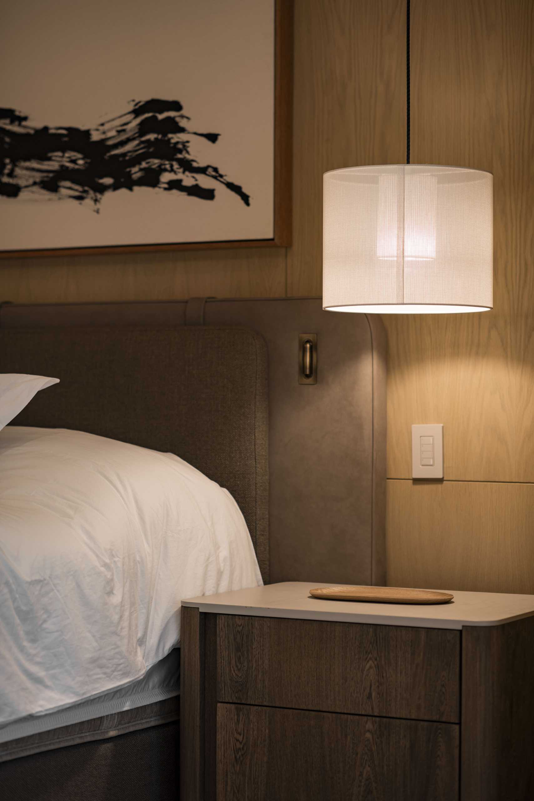 A modern primary bedroom with a pendant light as a bedside lamp.