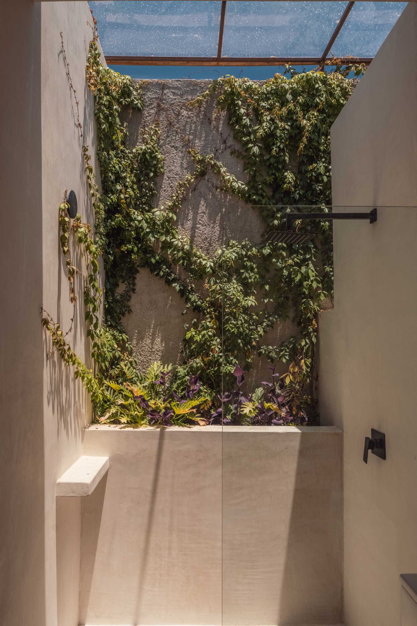 A modern bathroom includes a wall with ivy, creating a feeling of being outdoors.