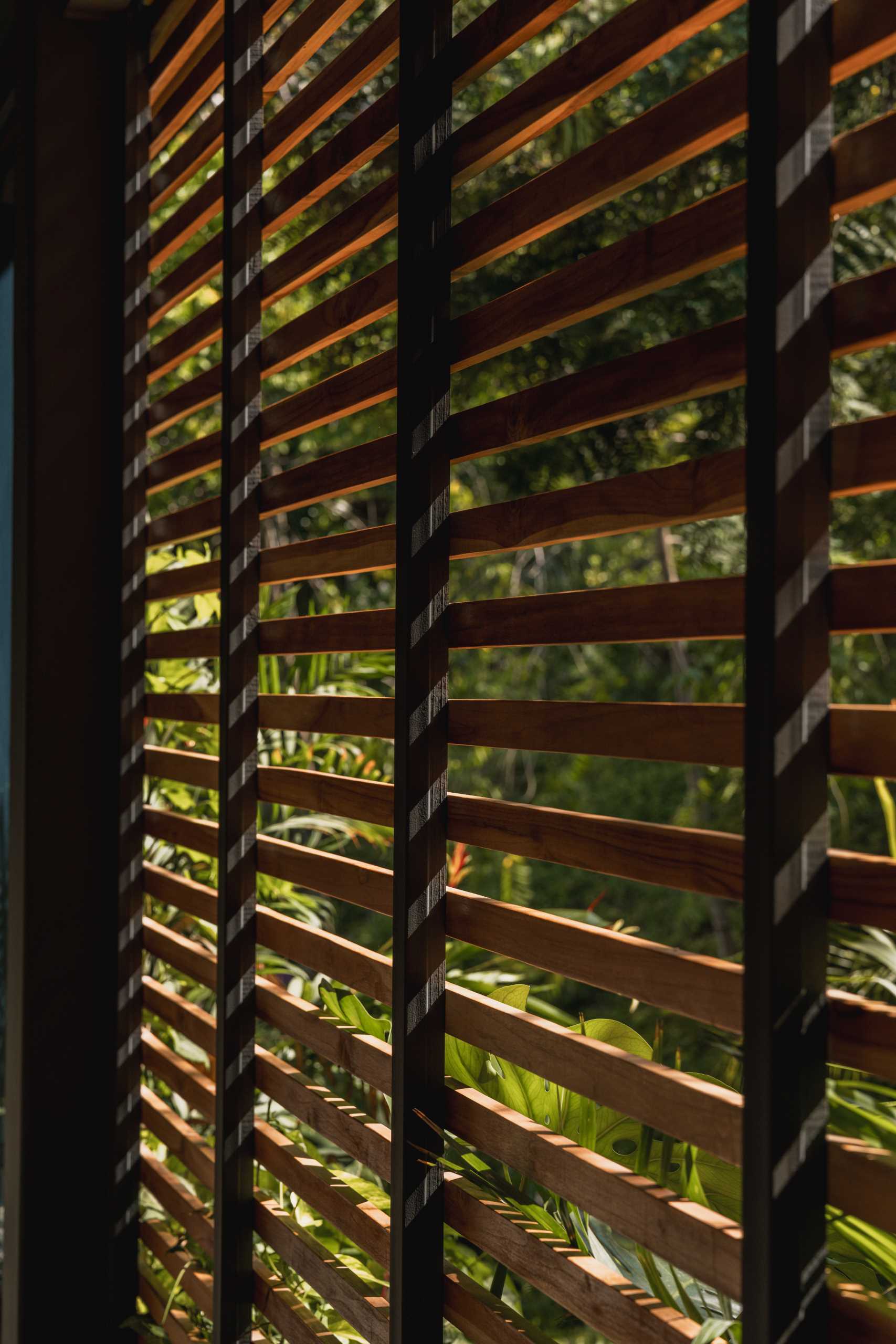 The wood slats featured on some of the walls help this modern home blend into its tropical surroundings.