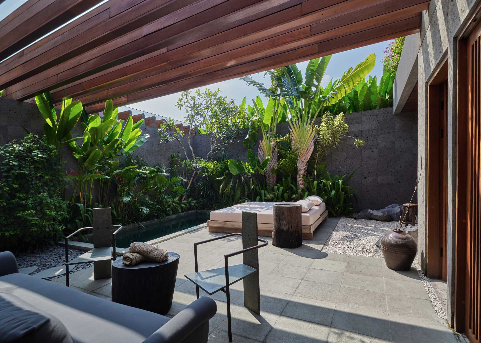 An outdoor living room with a water feature, daybed and lounge area.