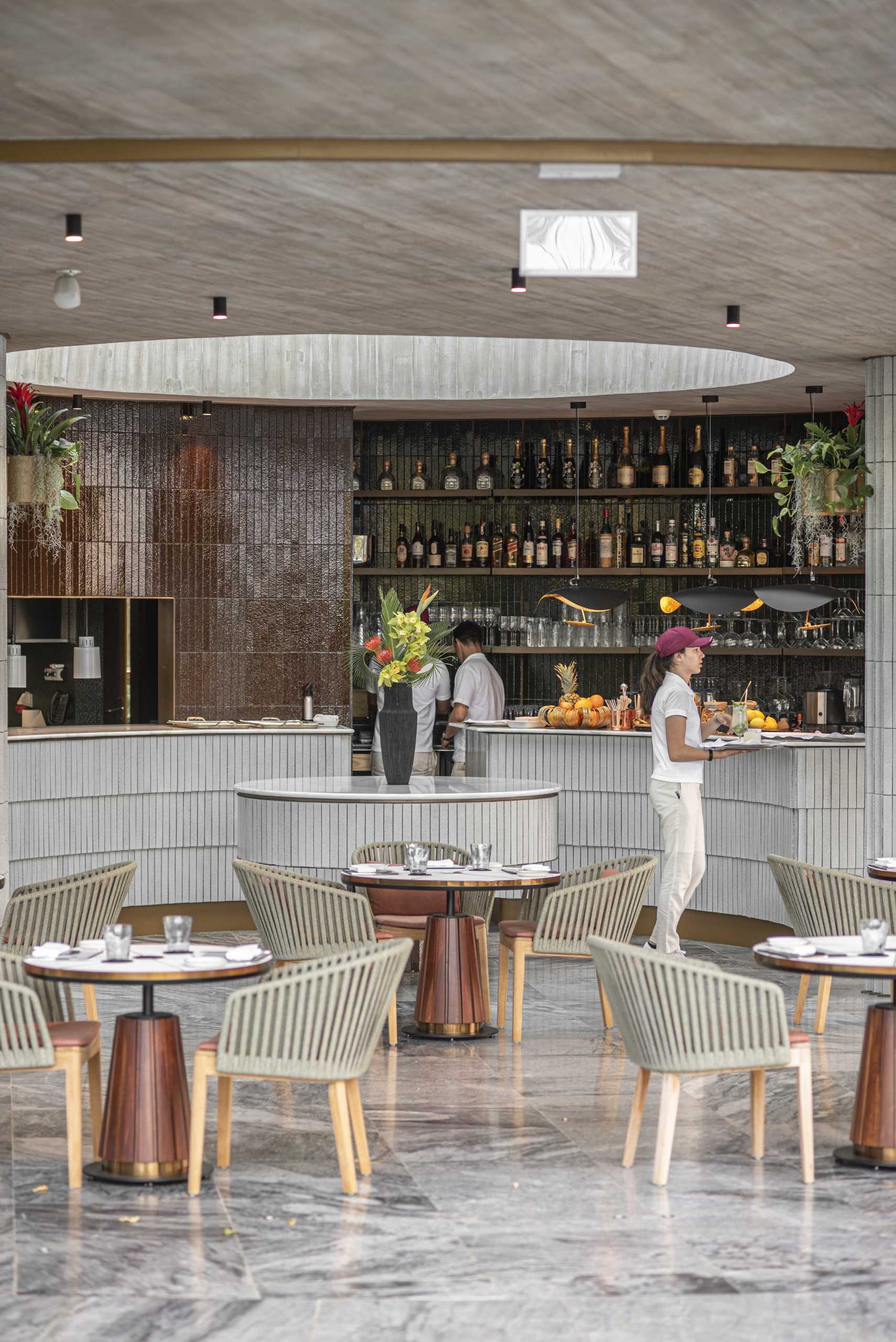 The terracotta tiles in shades of green and brown, designed by Openbook and produced by Viúva Lamego, blend in with the green of the surrounding garden, while the shape of the bar reflects that of the building.