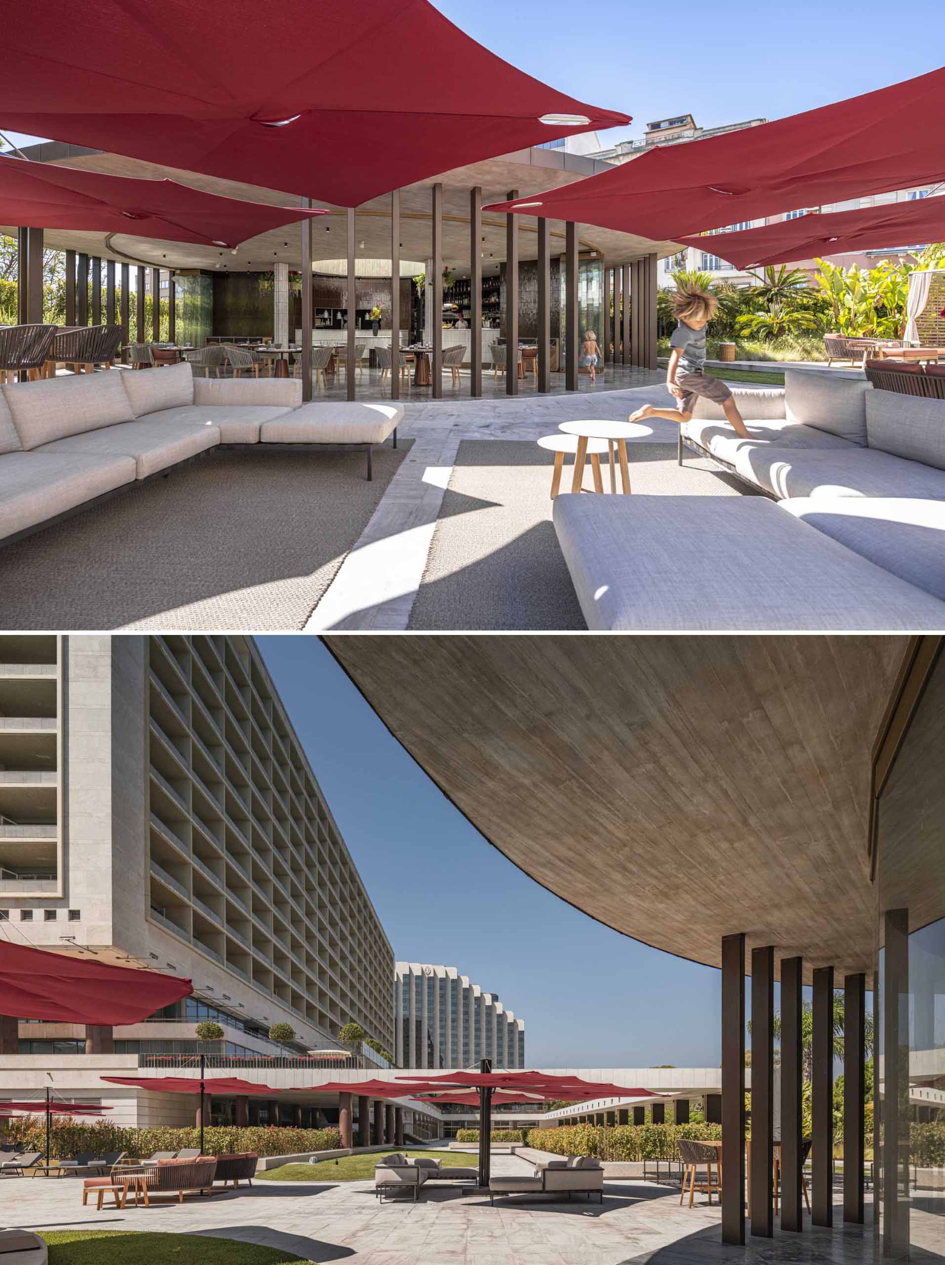 A hotel bar with a curved design has glass walls that open to the surrounding terrace.