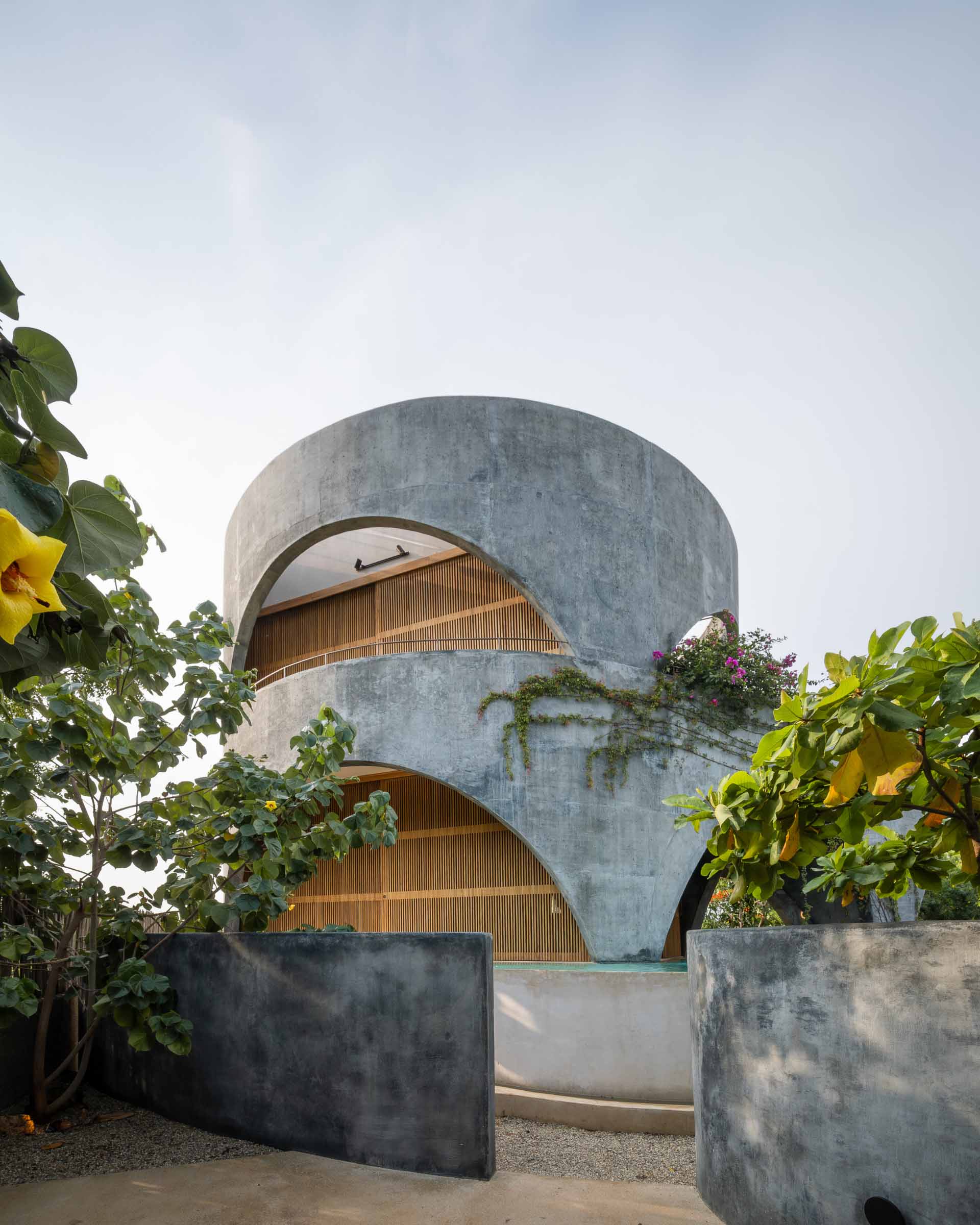 A modern concrete home with a round design and open arches.