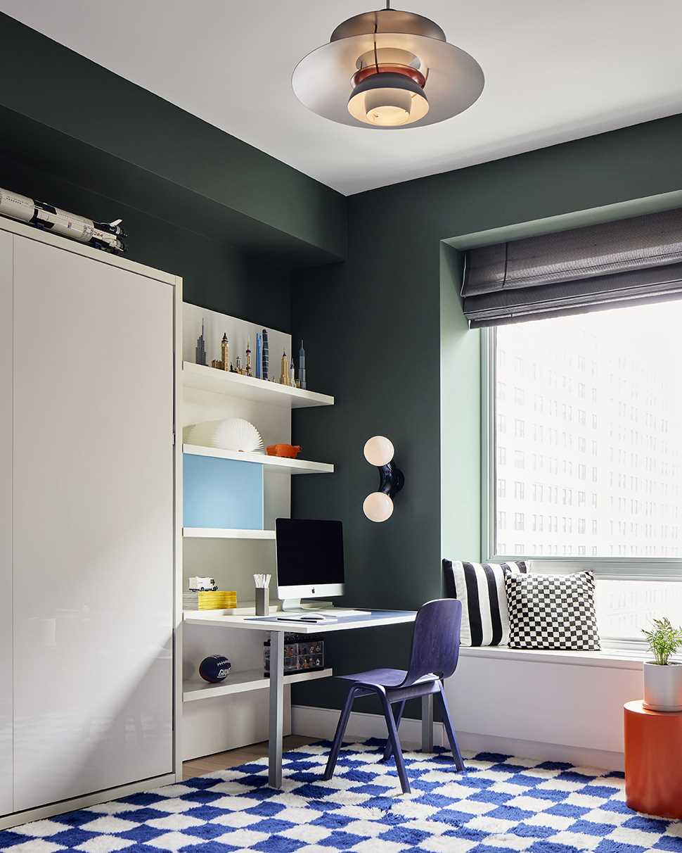 In this kids' bedroom, deep green walls contrast the white furniture, that also hides a murphy bed.