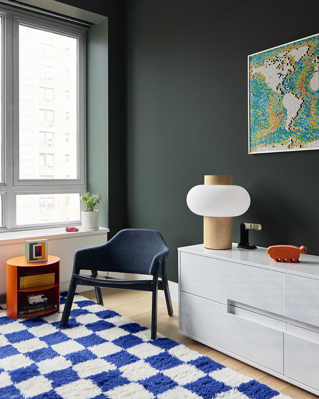 In this kids' bedroom, deep green walls contrast the furniture, that also hides a murphy bed.