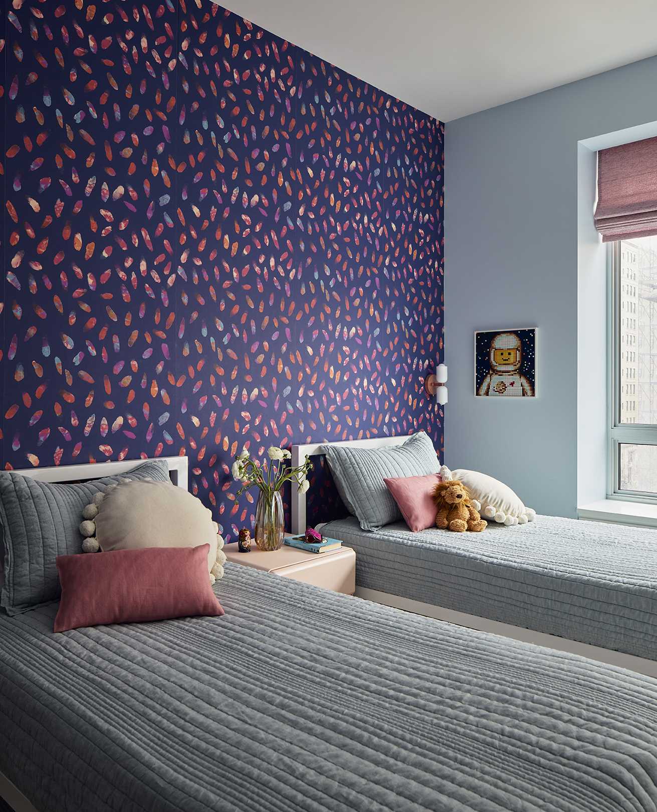 This children's bedroom has a vibrant deep blue wallpaper with lively pink gestural brushstrokes.