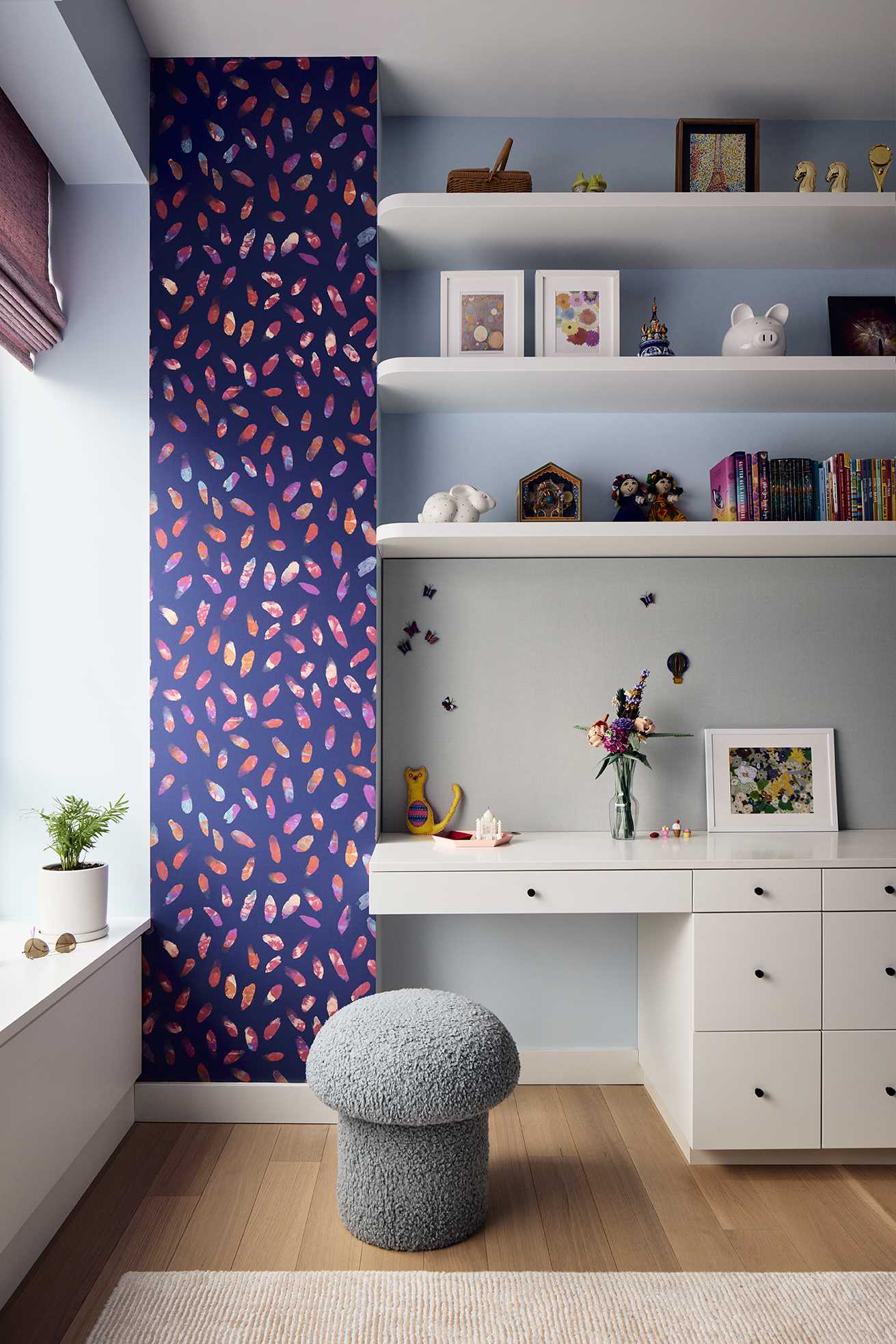 This children's bedroom has a vibrant deep blue wallpaper with lively pink gestural brushstrokes.