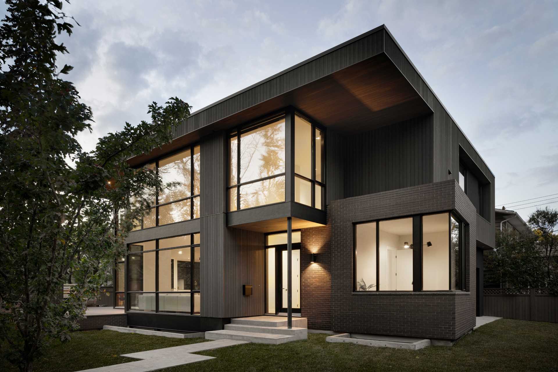 A modern home with a dark wood exterior complements the surrounding forest.