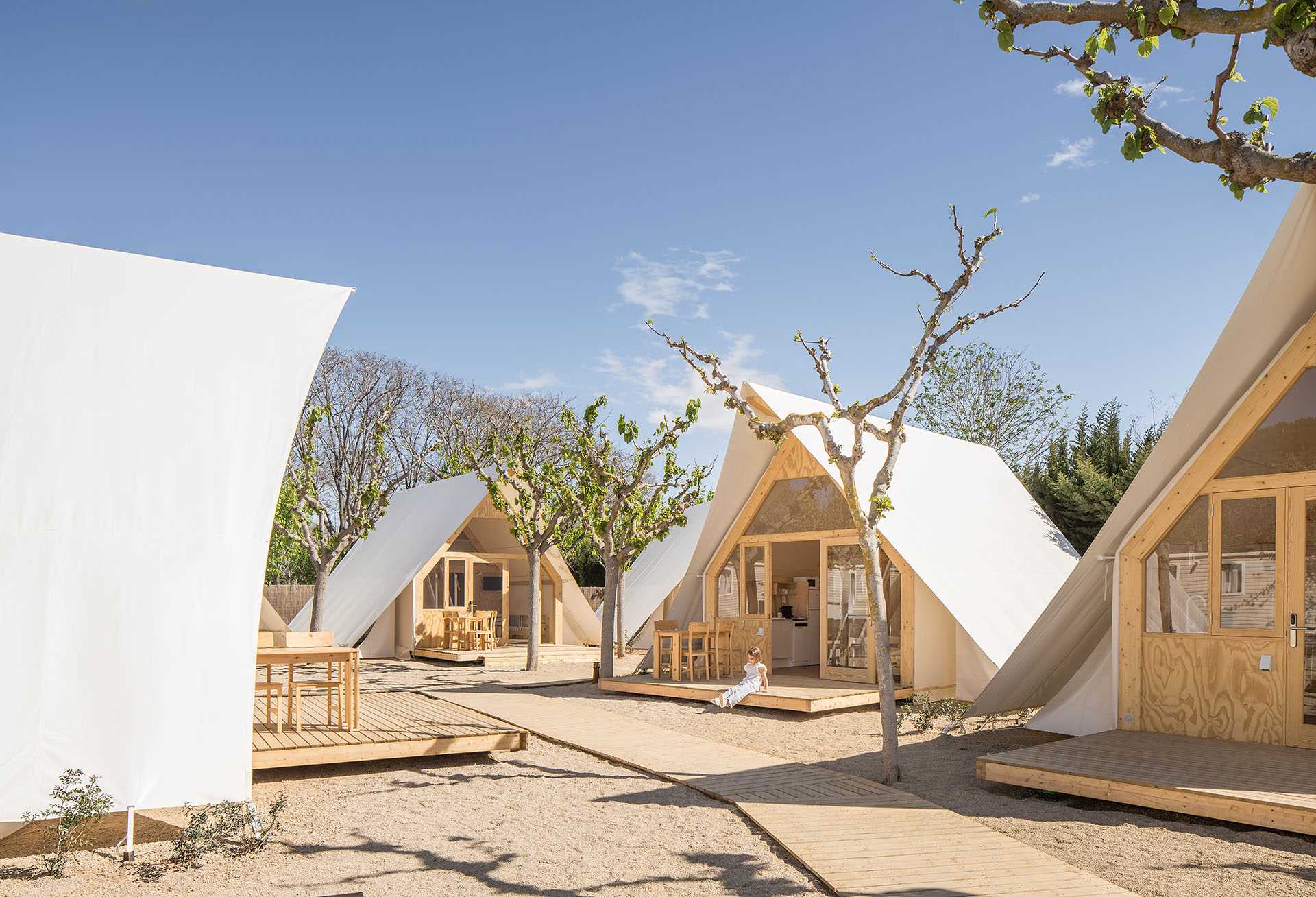 A modern glamping tent designed with a wood structure, windows, and white exterior.