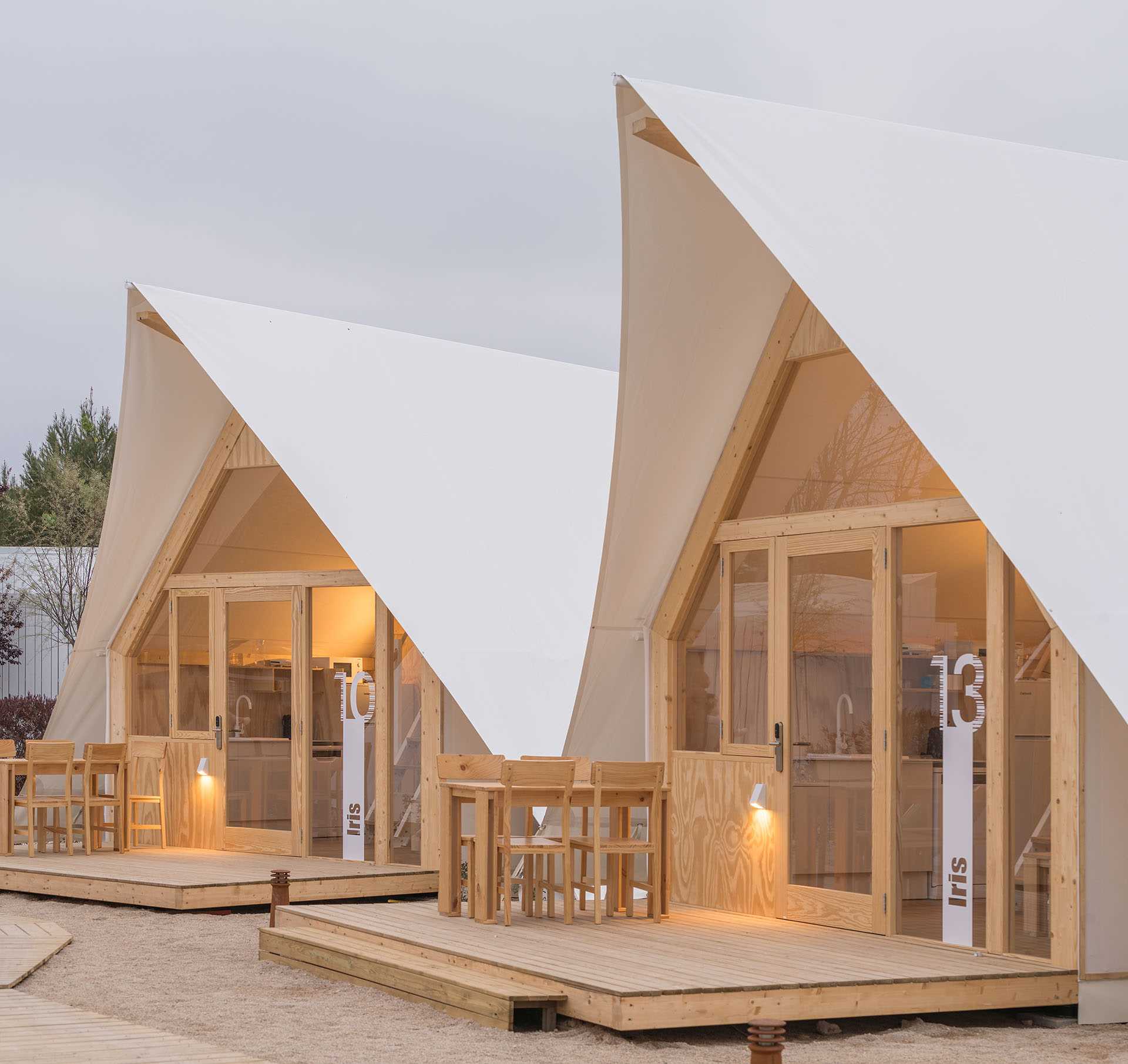 A modern glamping tent designed with a wood structure, windows, and white exterior.