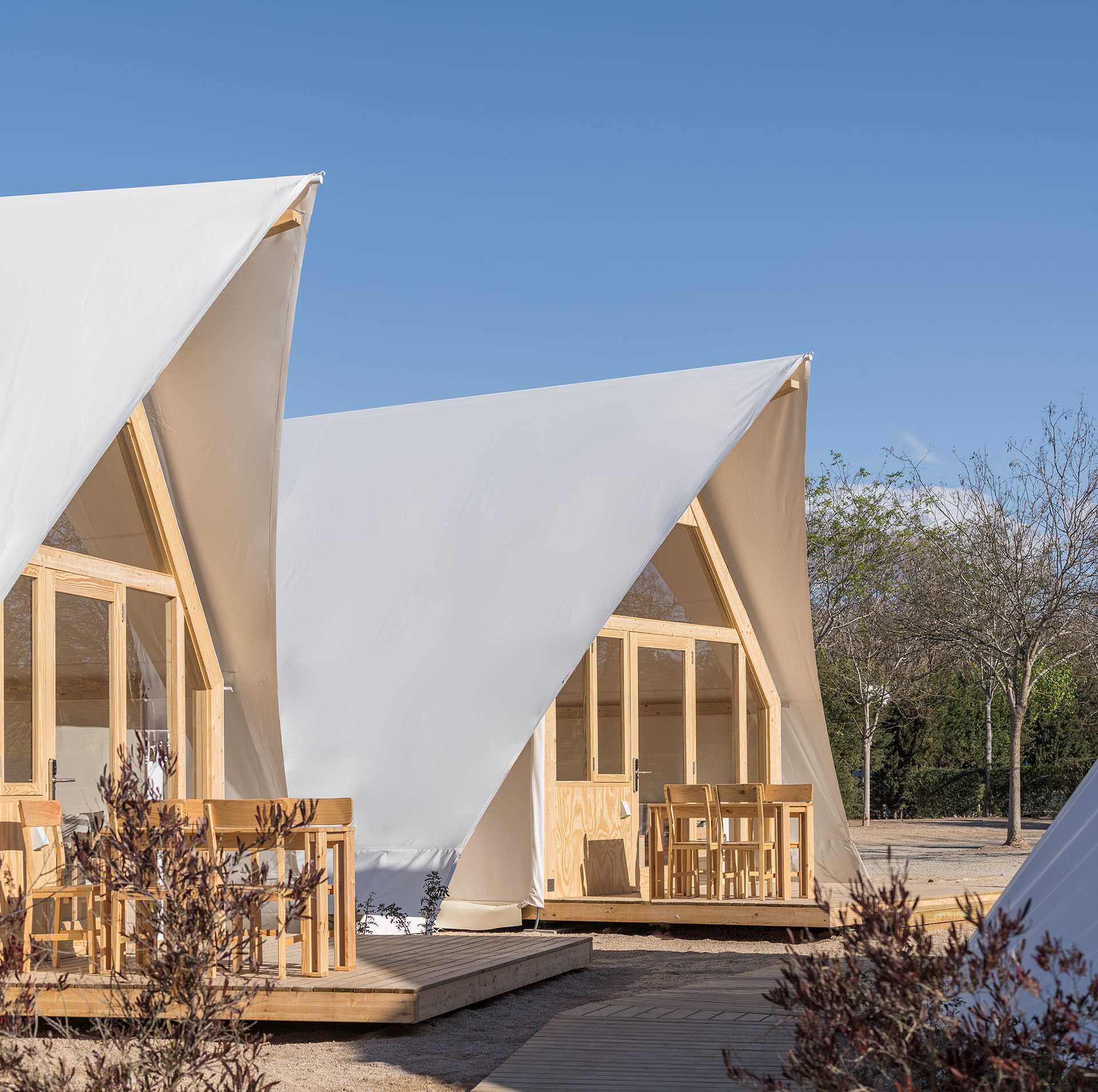 A modern glamping tent designed with a wood structure, windows, and white exterior.