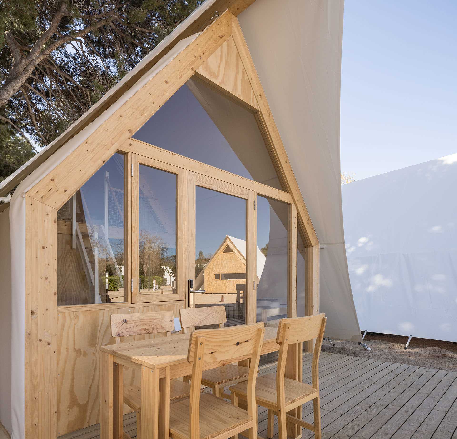 A modern glamping tent designed with a wood structure, windows, and white exterior.