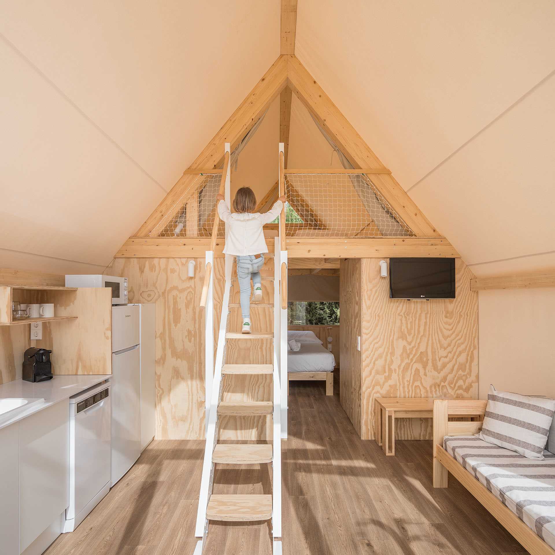 A modern glamping tent with a living room, kitchen, main bedroom, bathroom, and second lofted bedroom.