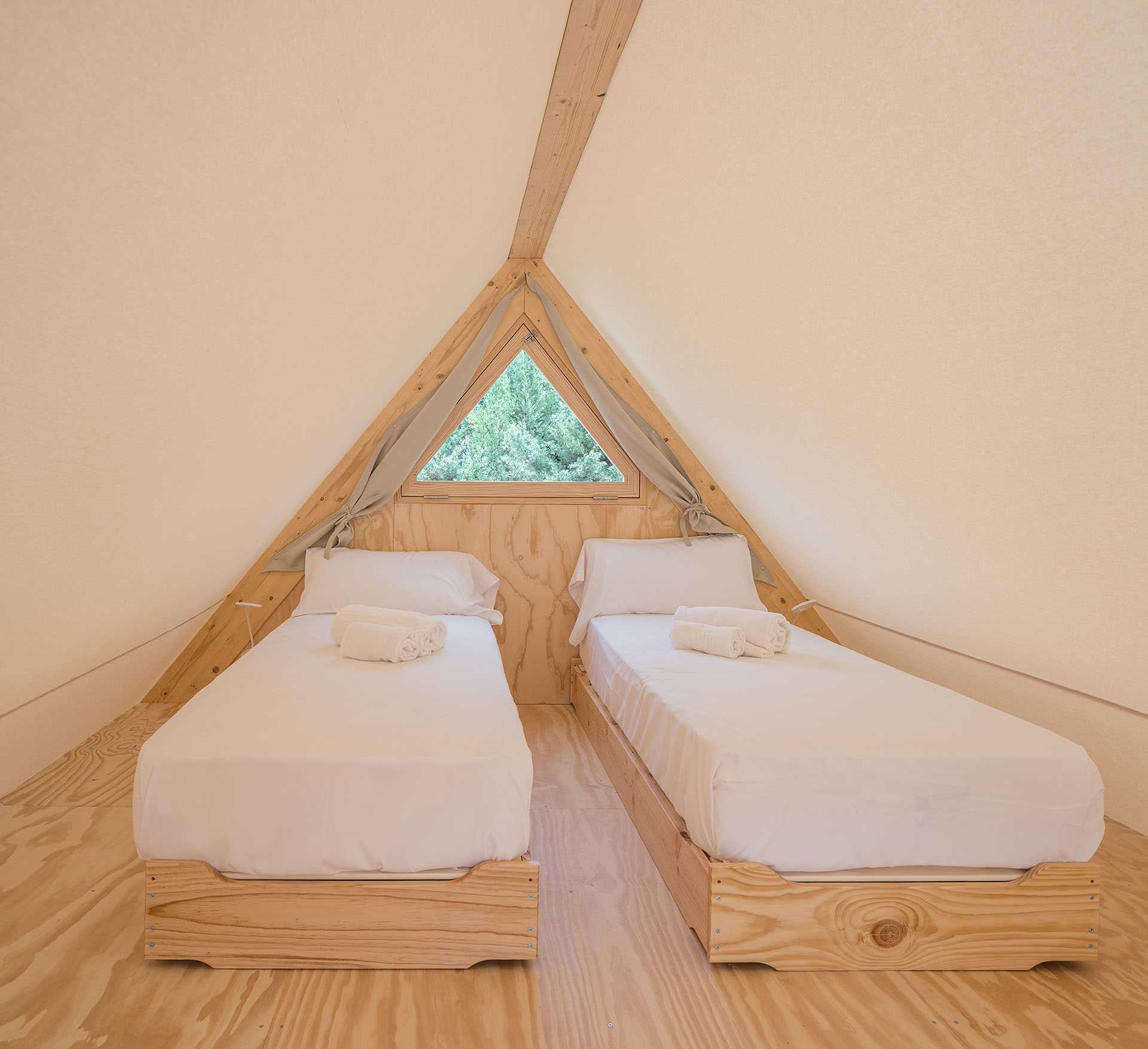 A modern glamping tent with a living room, kitchen, main bedroom, bathroom, and second lofted bedroom.