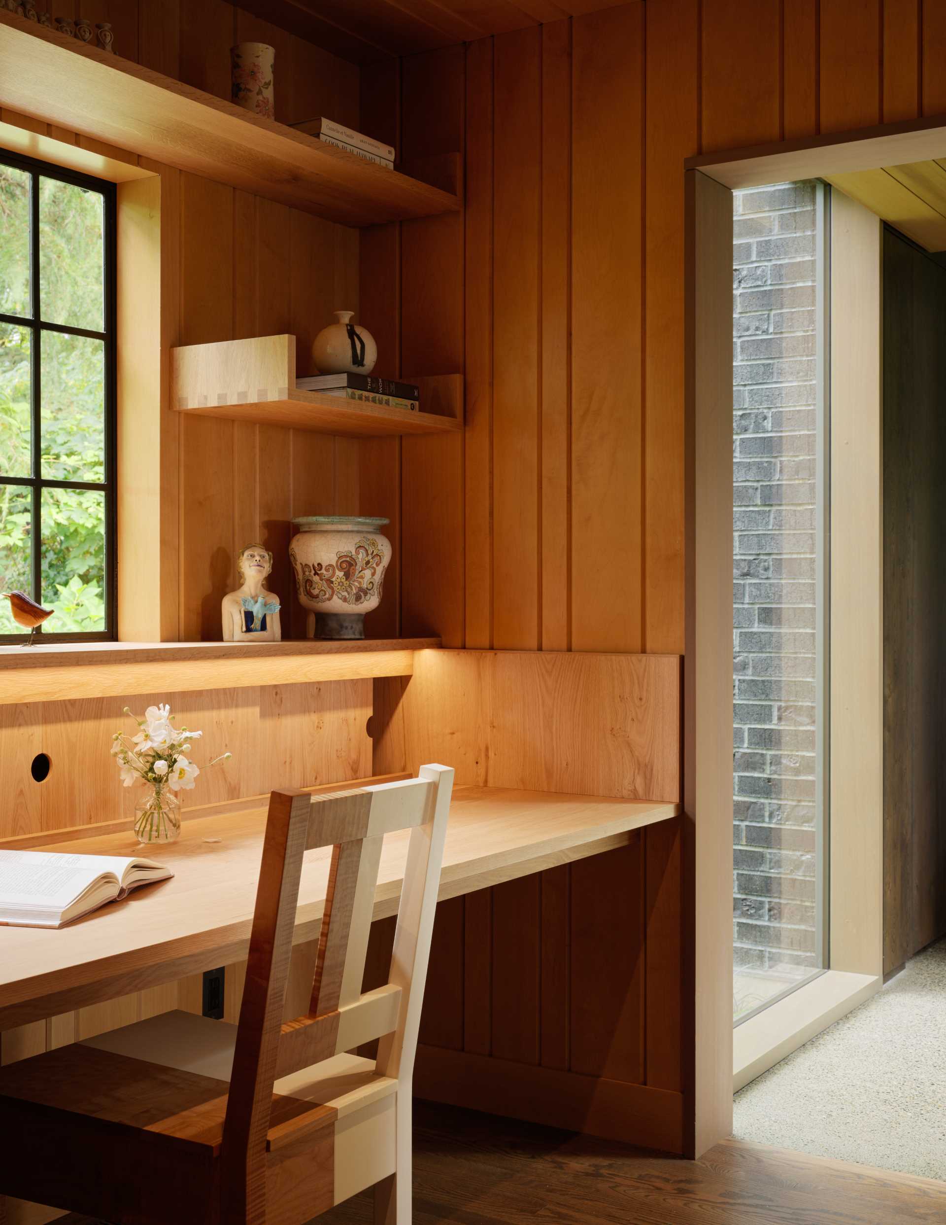 A contemporary home office with built-in desk and shelving.