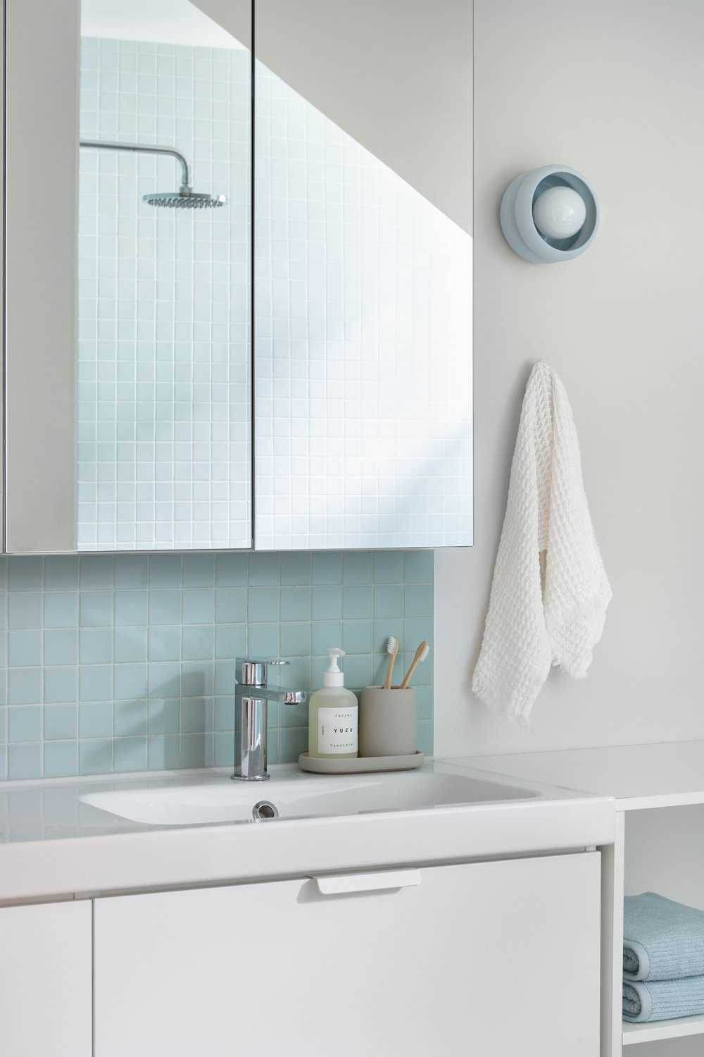 Square turquoise tiles add a subtle pop of color in this coastal-inspired bathroom.